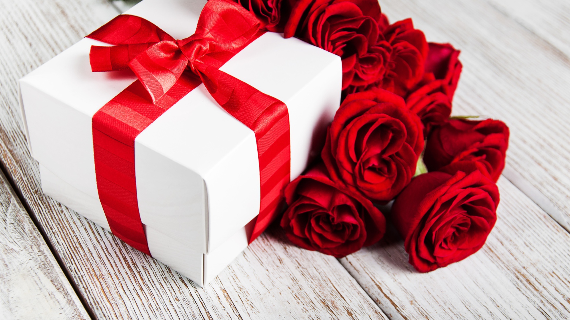 Красные розы на столе с подарком с красной лентой