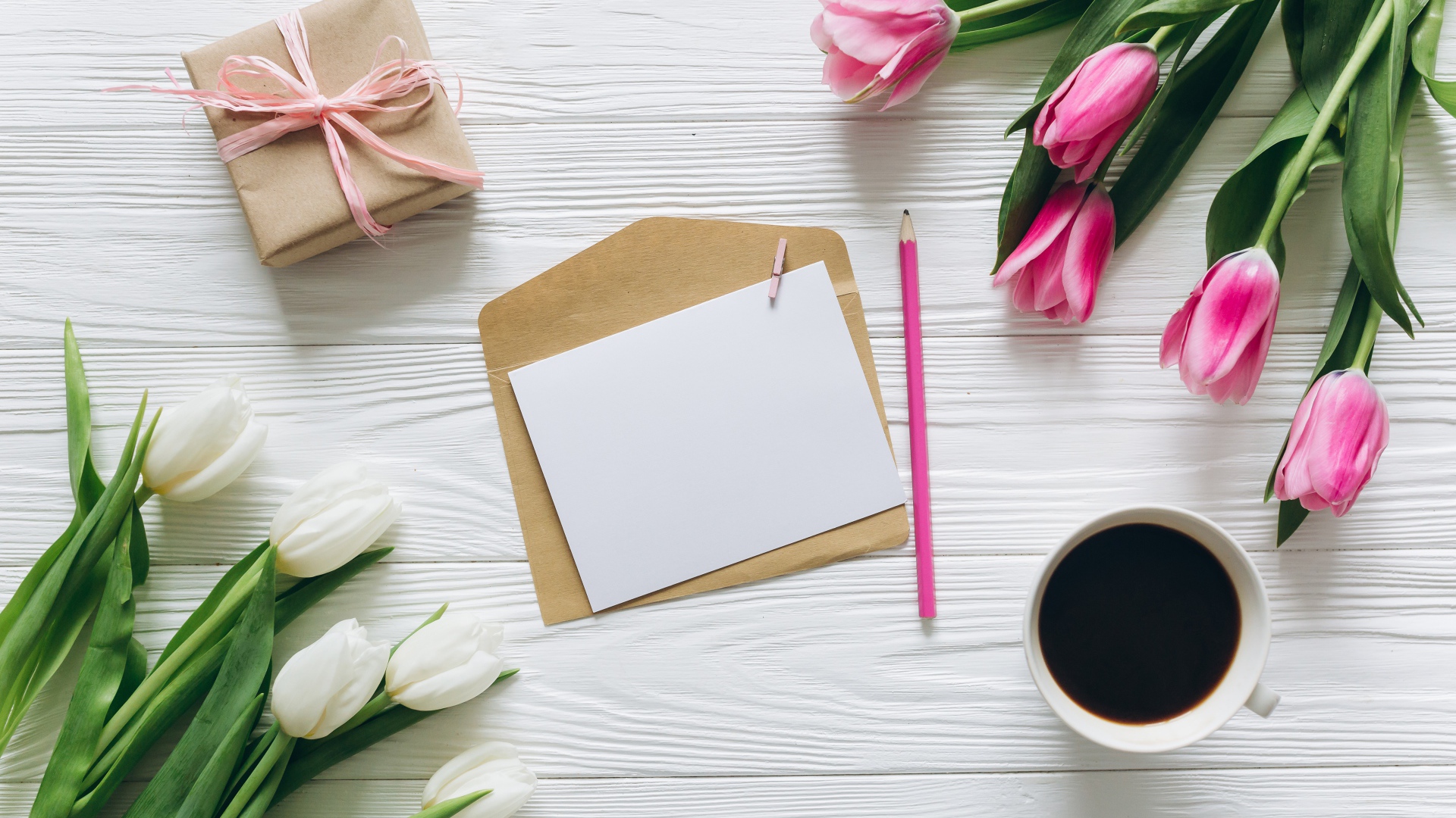 Два букета тюльпанов на столе с подарком, кофе и письмом