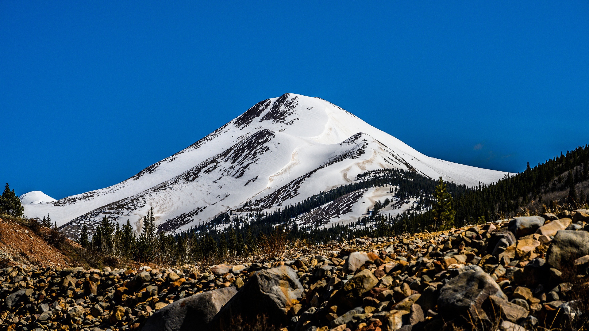 Высокая заснеженная гора под голубым небом