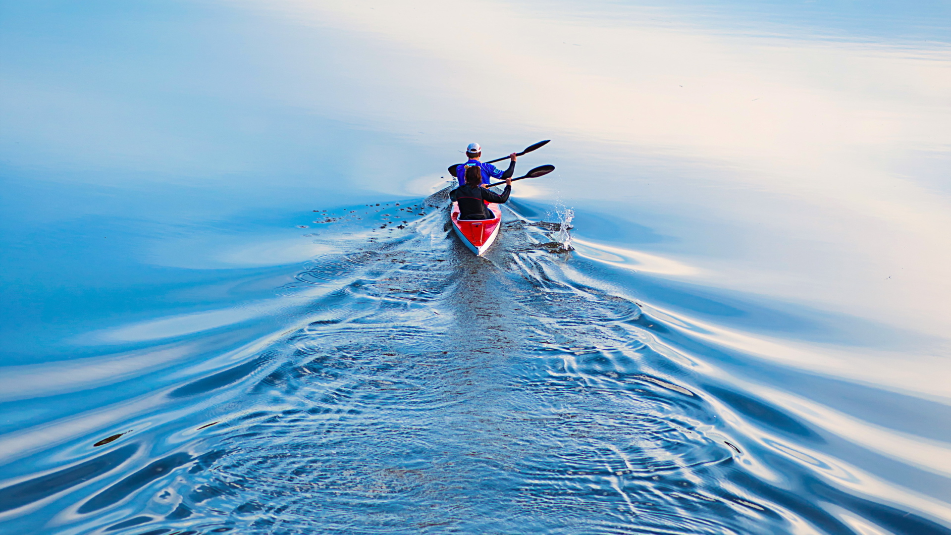 Два спортсмена на лодке плывут по реке 