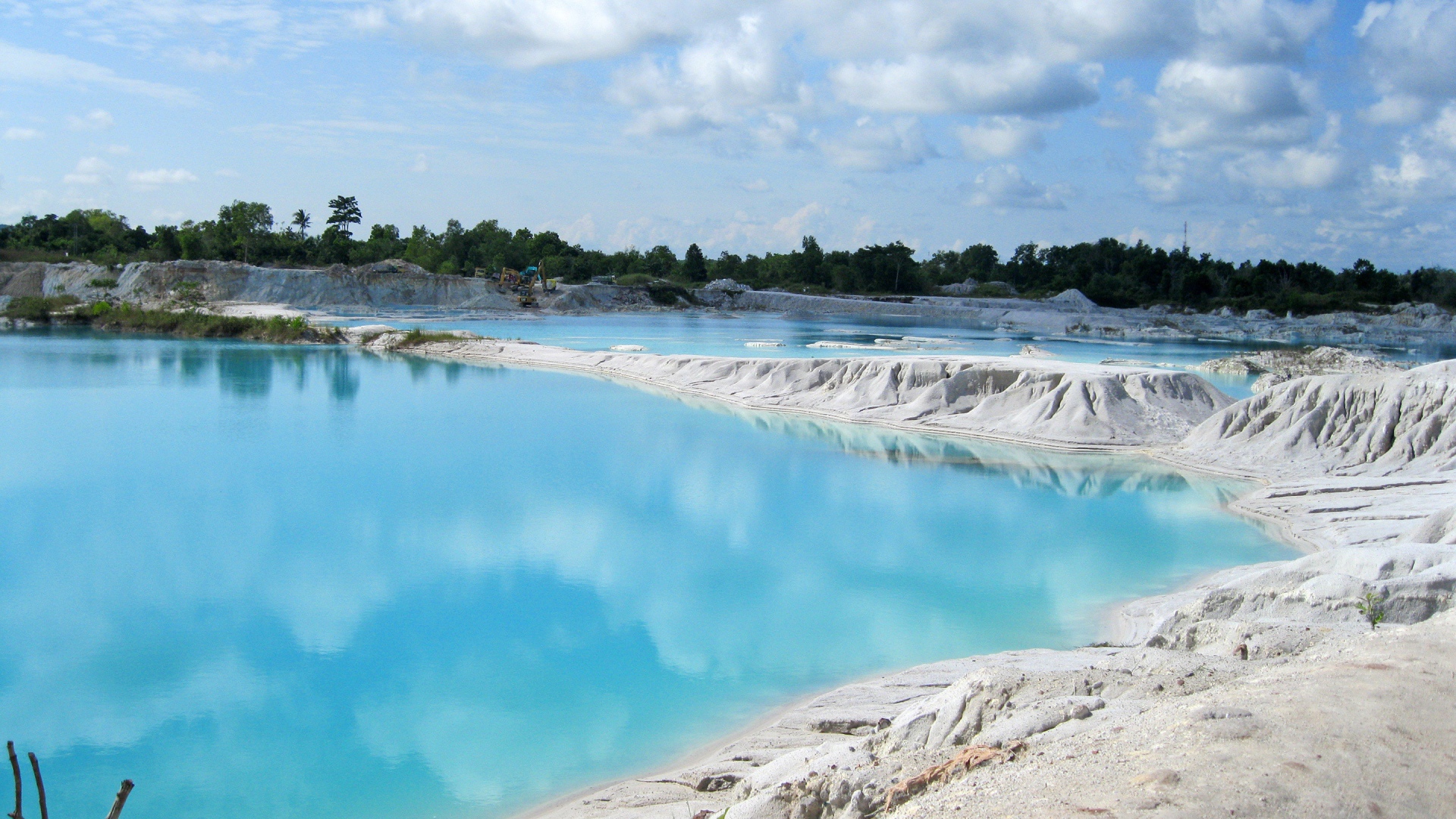 Белый песок на берегу водоема с голубой водой 