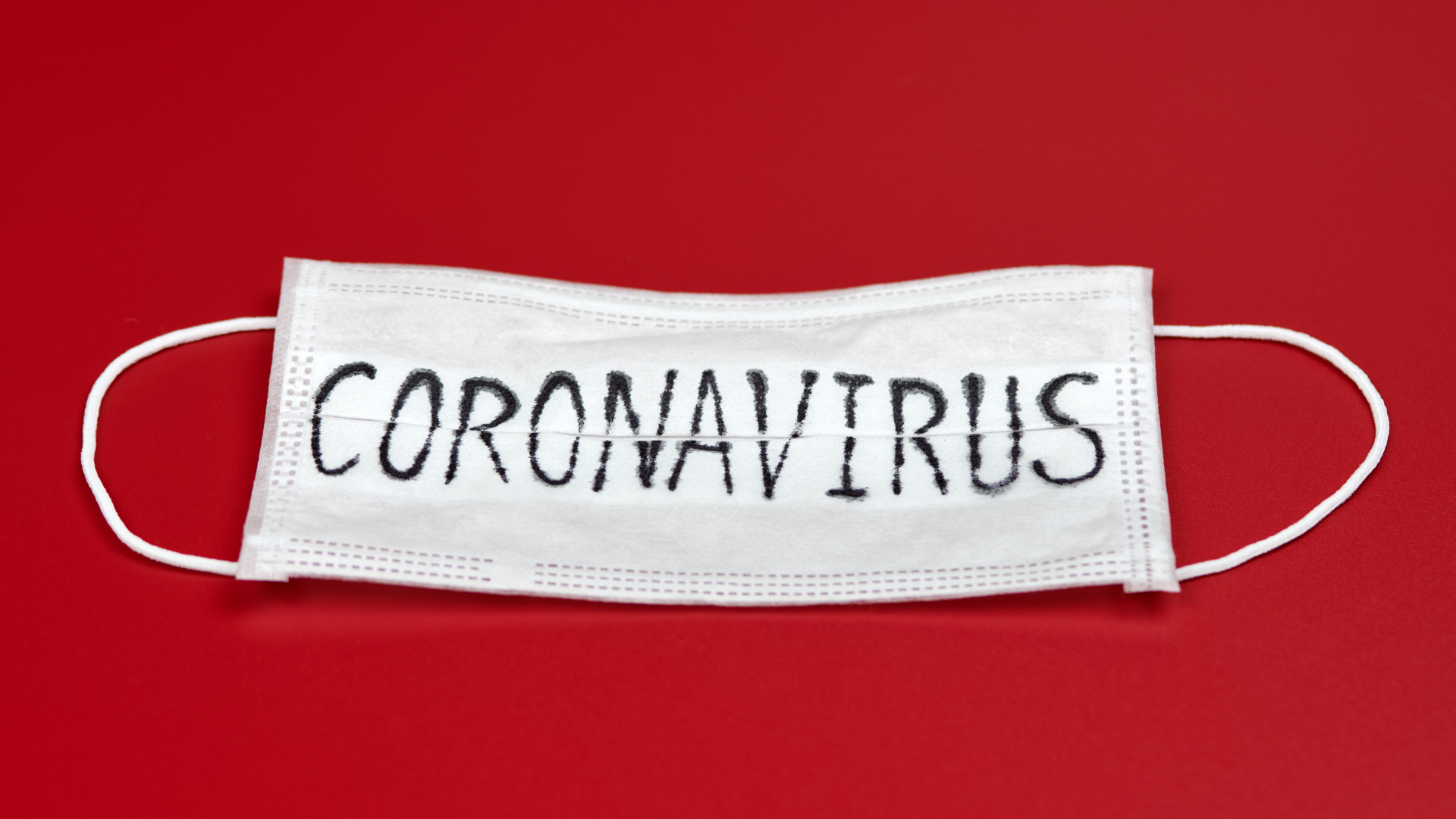 Медицинская маска с надписью коронавирус Covid-19 на красном фоне