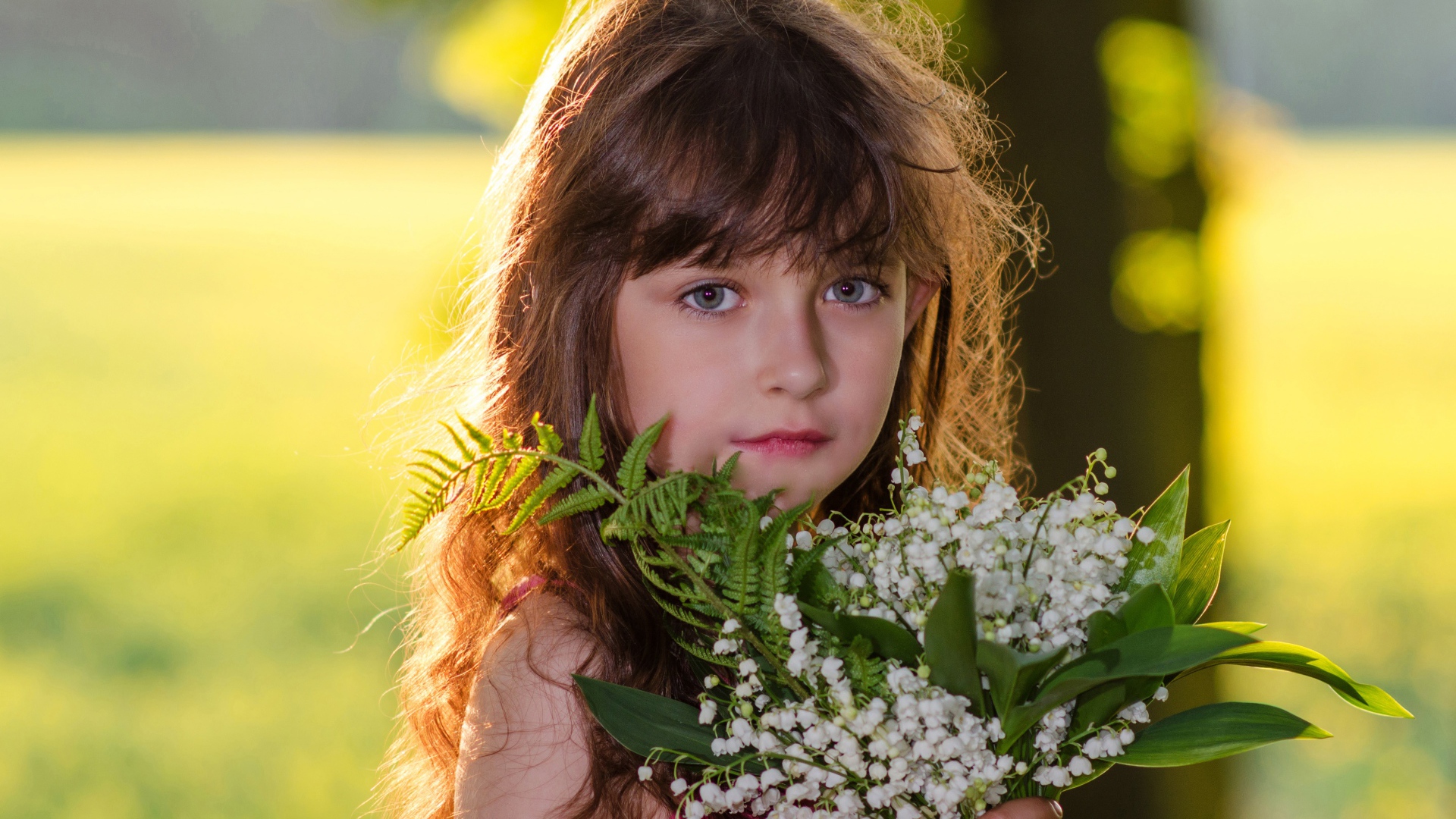 Красивая маленькая девочка с букетом ландышей в руке