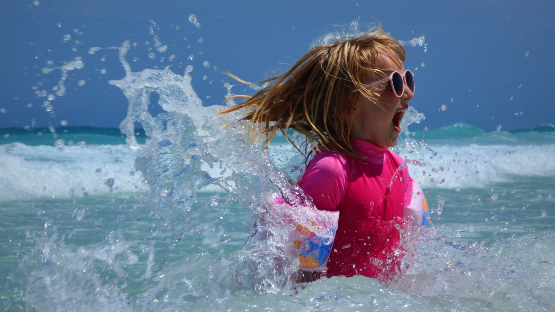 Веселая маленькая девочка купается в море летом