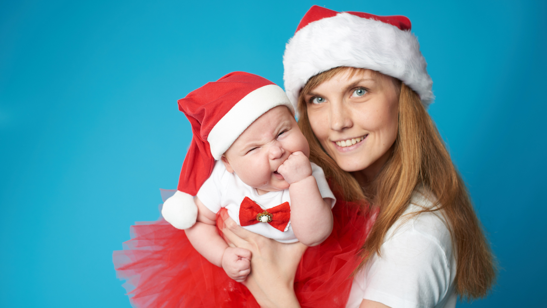 Смешной ребенок в новогоднем костюме на руках у мамы 