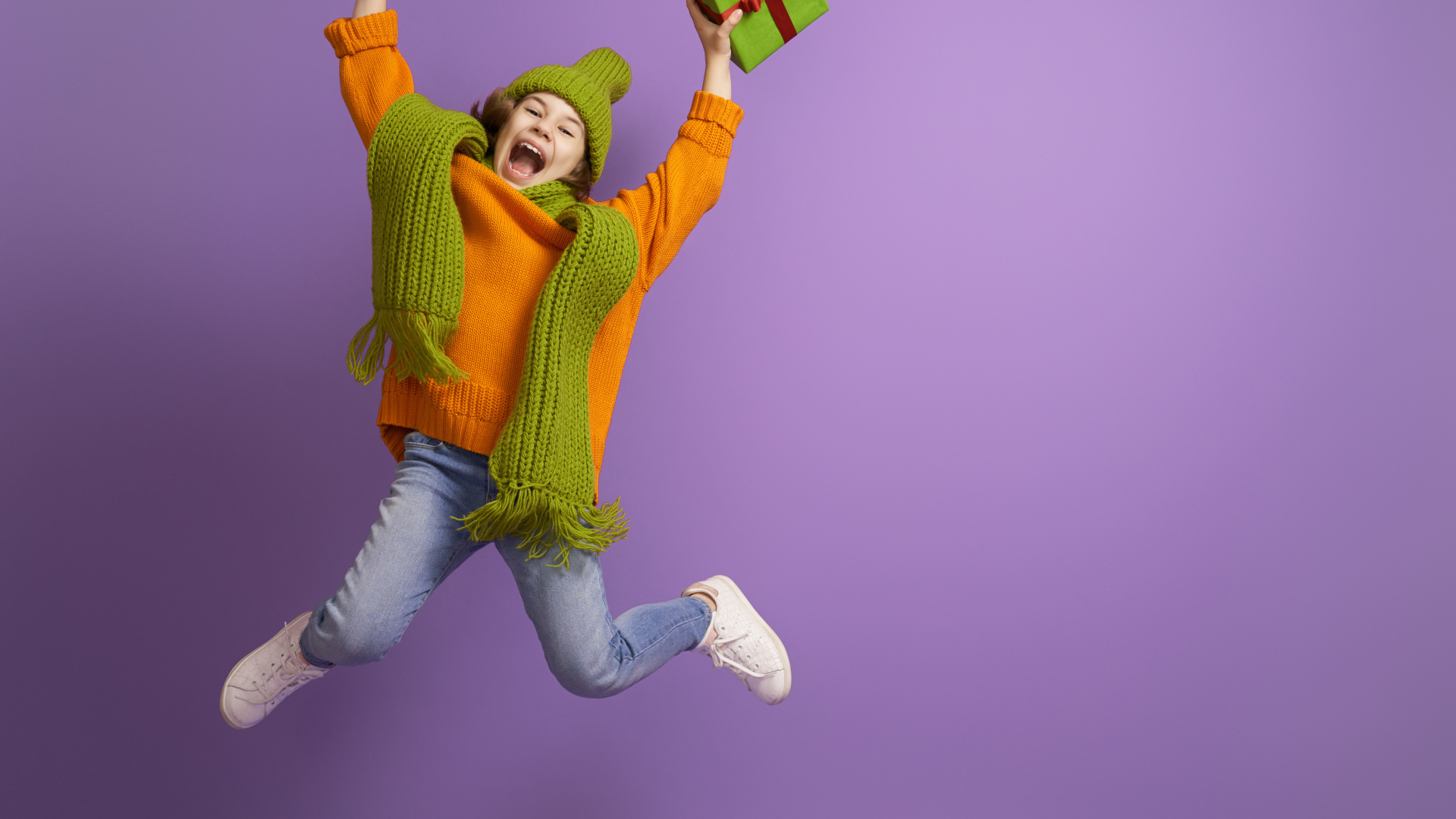 Счастливая девочка с подарком в руке на фиолетовом фоне