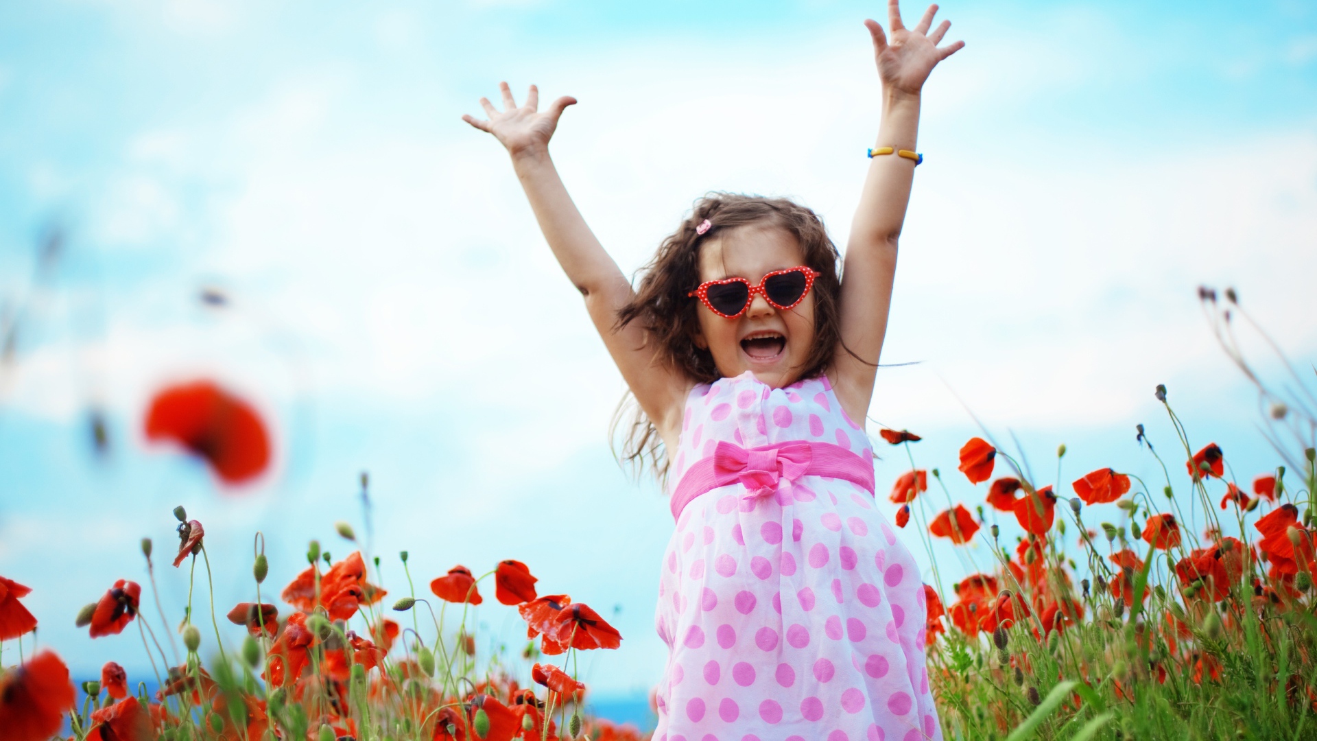 Счастливая маленькая девочка в платье на поле с маками