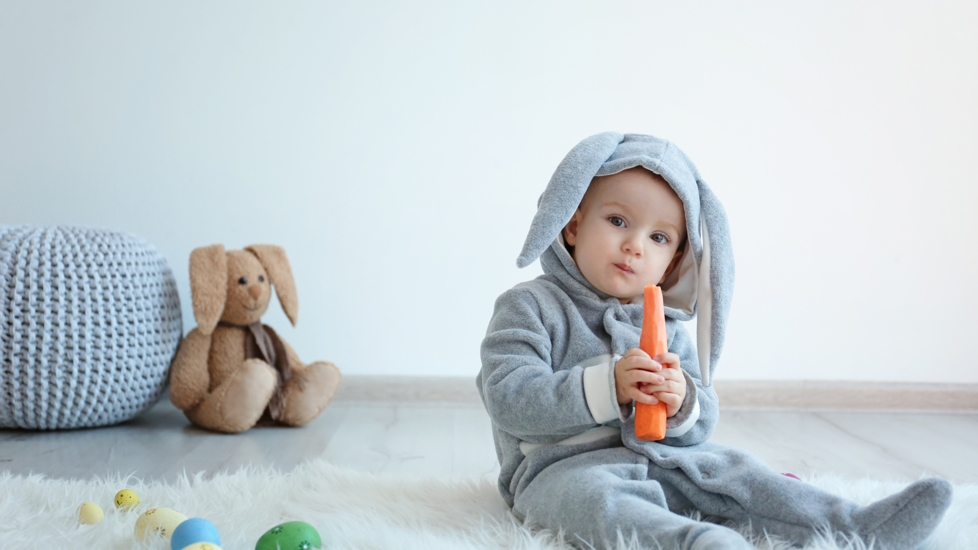 Маленький мальчик в костюме зайчика грызет морковь