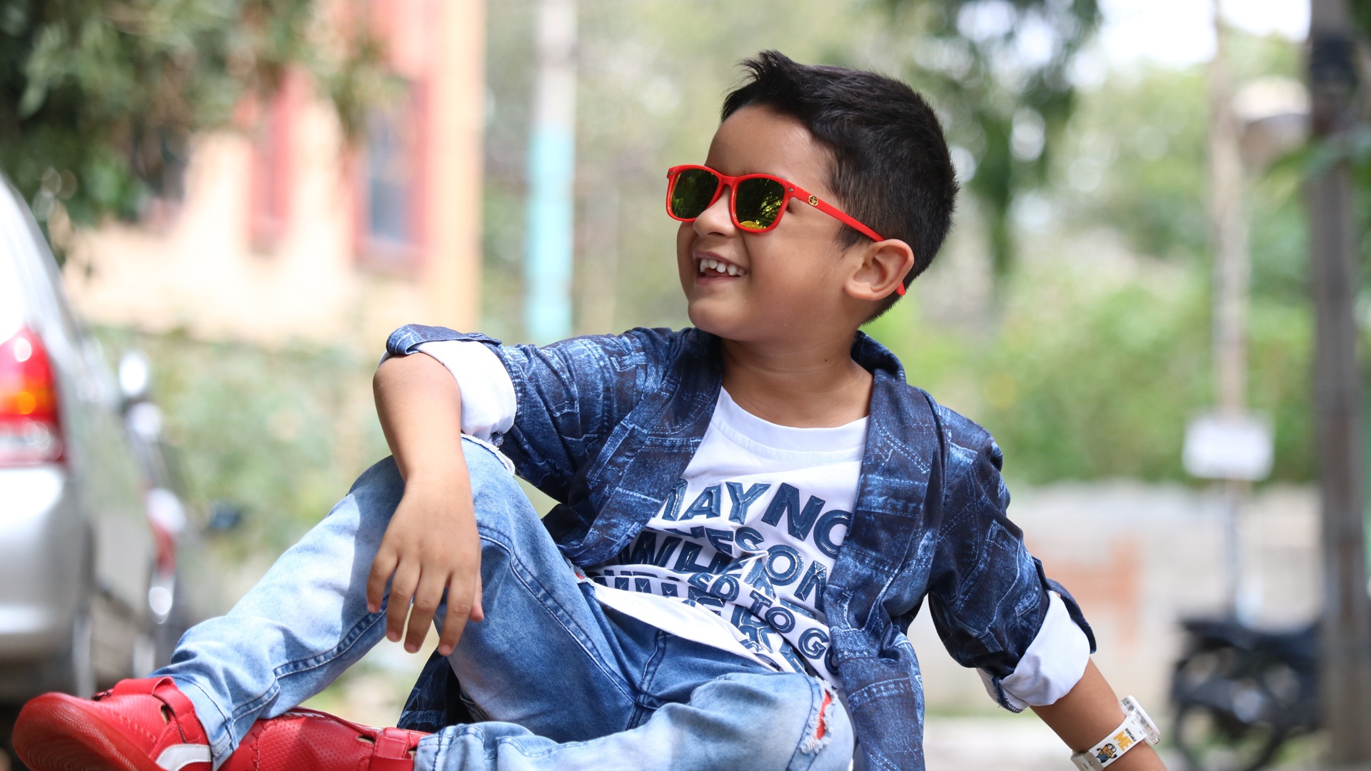 Маленький модный мальчик сидит на асфальте