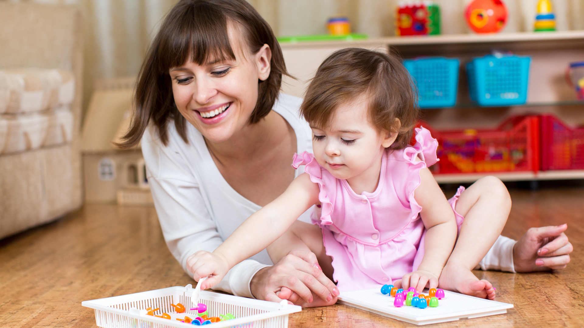 Маленькая девочка в розовом платье играет с мамой