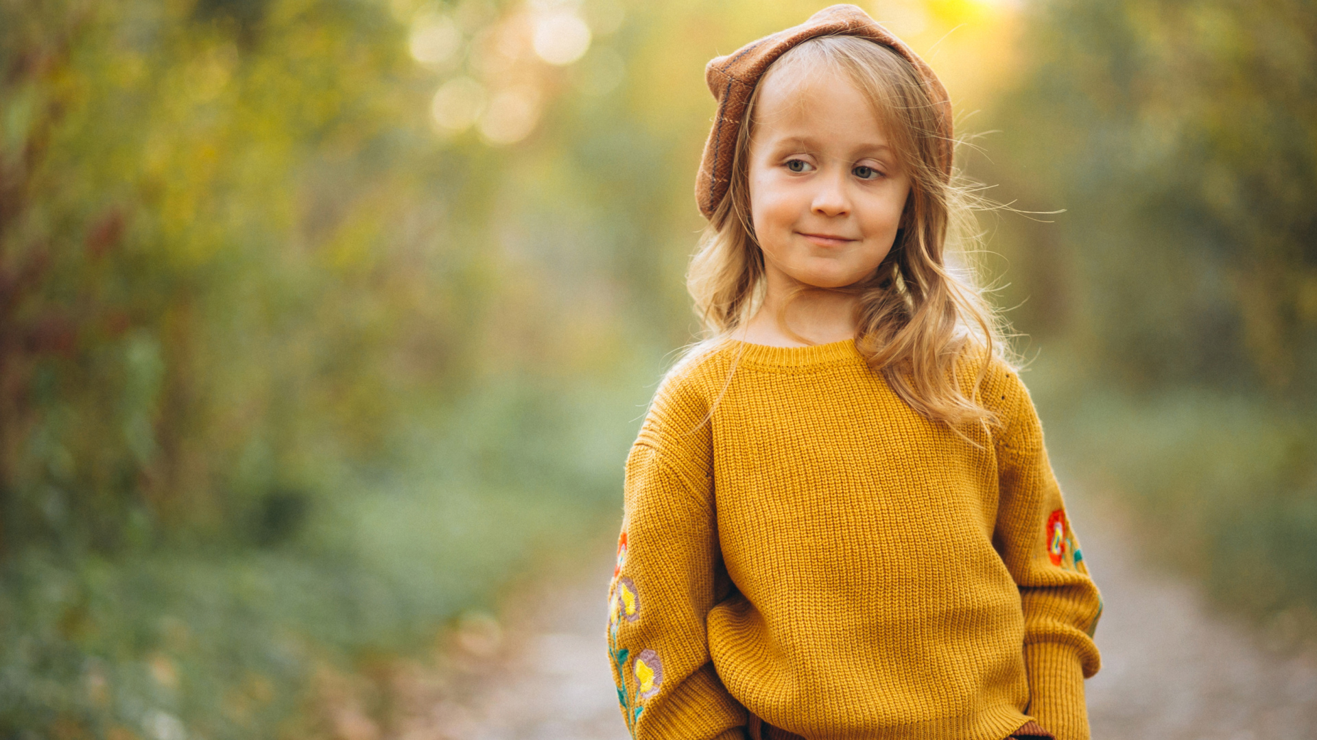 Маленькая девочка в свитере гуляет в лесу