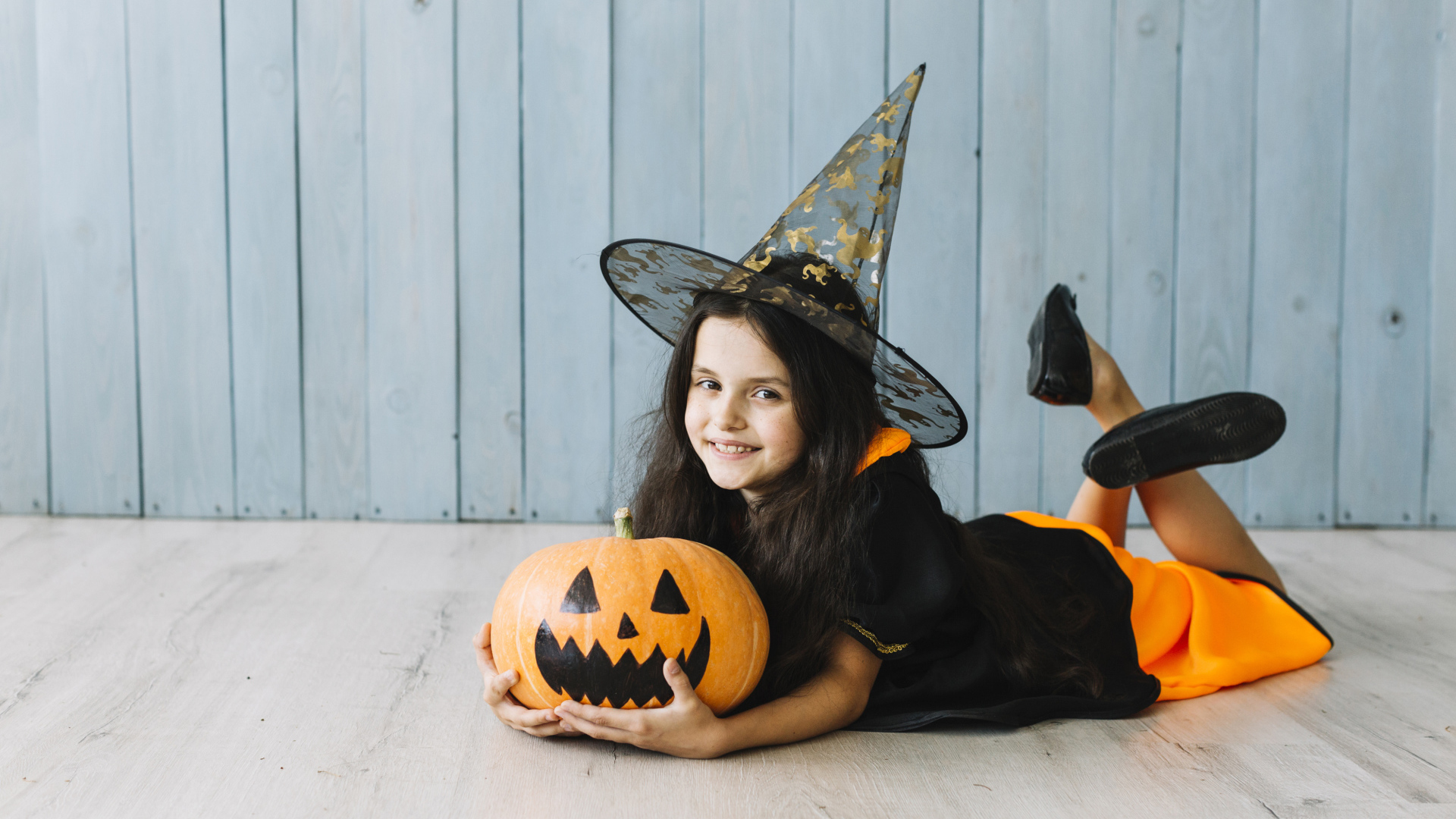 Маленькая девочка в костюме ведьмы с тыквой на Хэллоуин