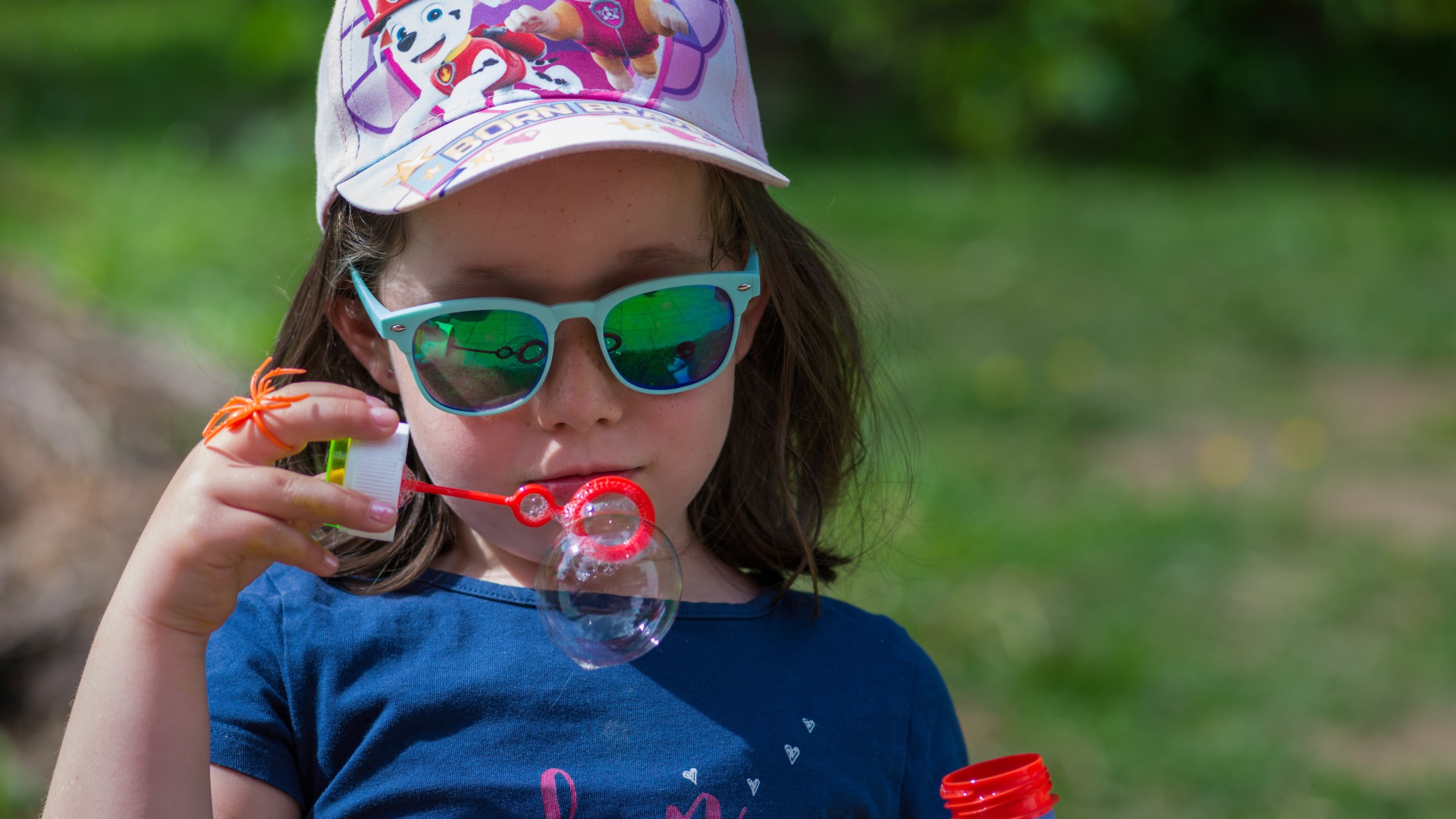 Маленькая девочка в очках с мыльными пузырями