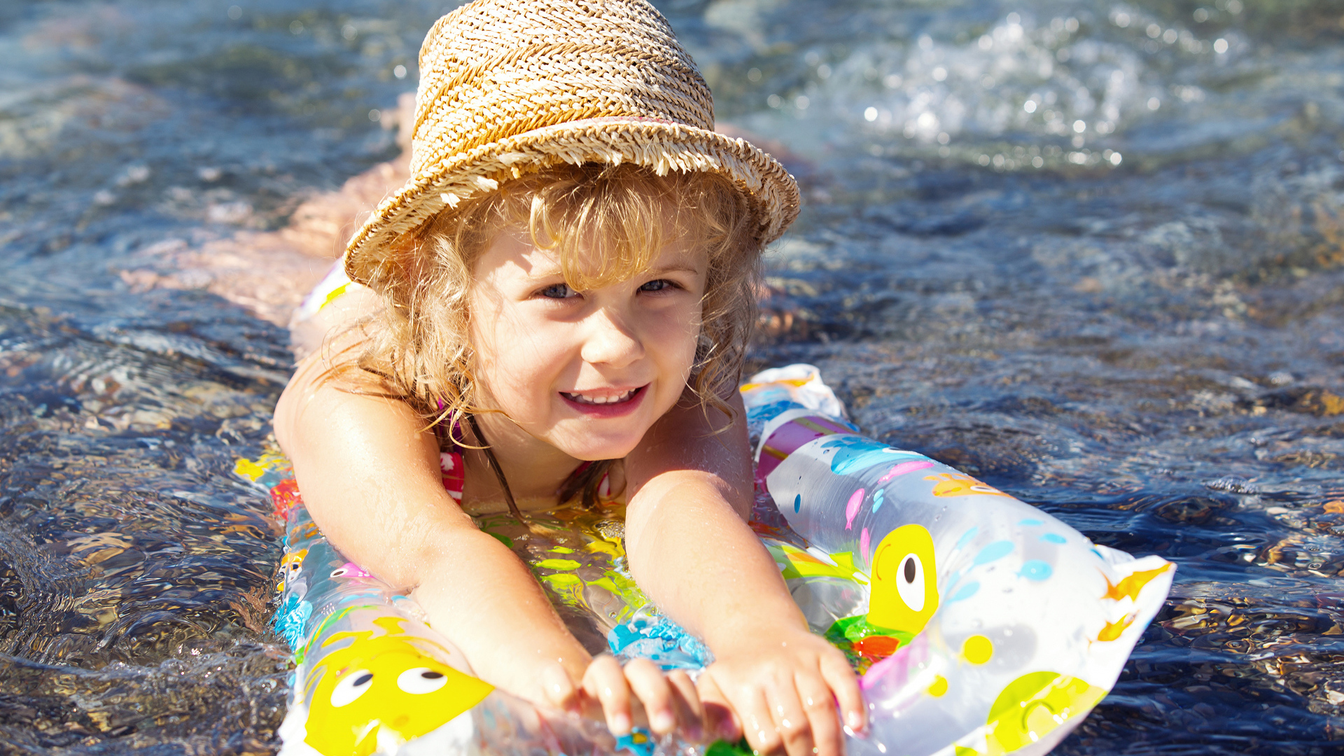 Маленькая девочка на надувном матрасе в воде