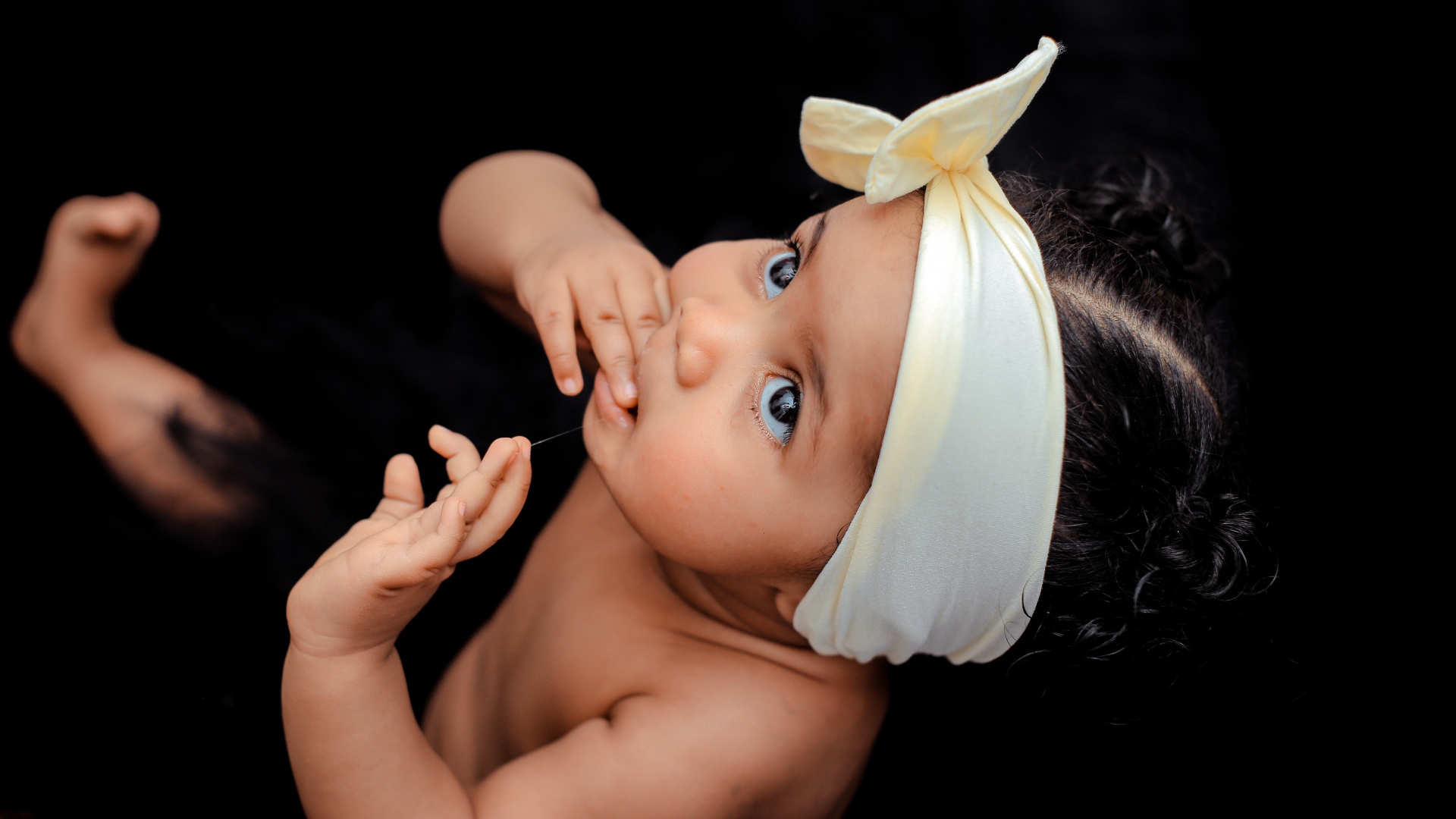 Маленькая девочка с повязкой на голове на черном фоне