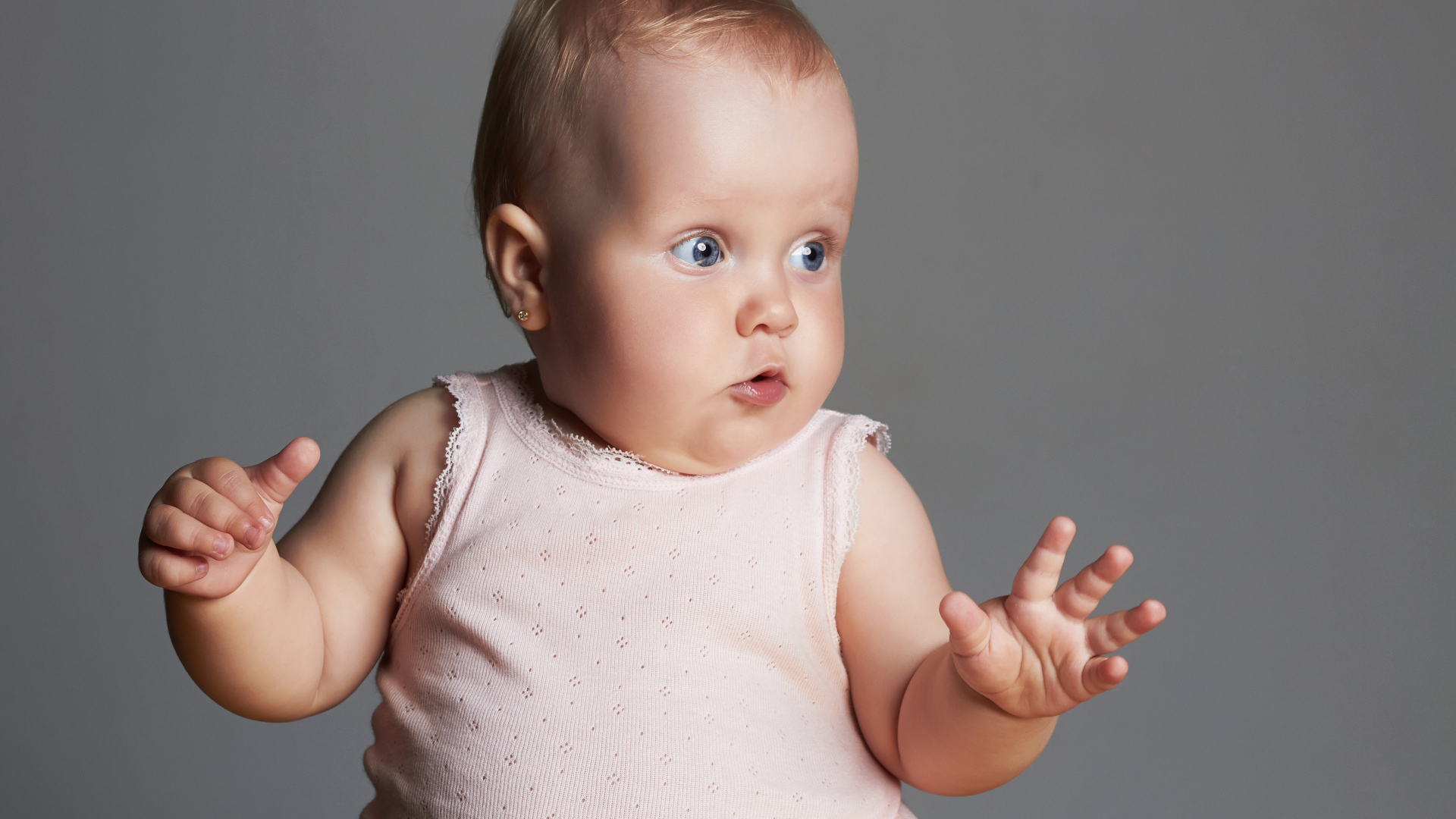 Удивленный маленький ребенок на сером фоне