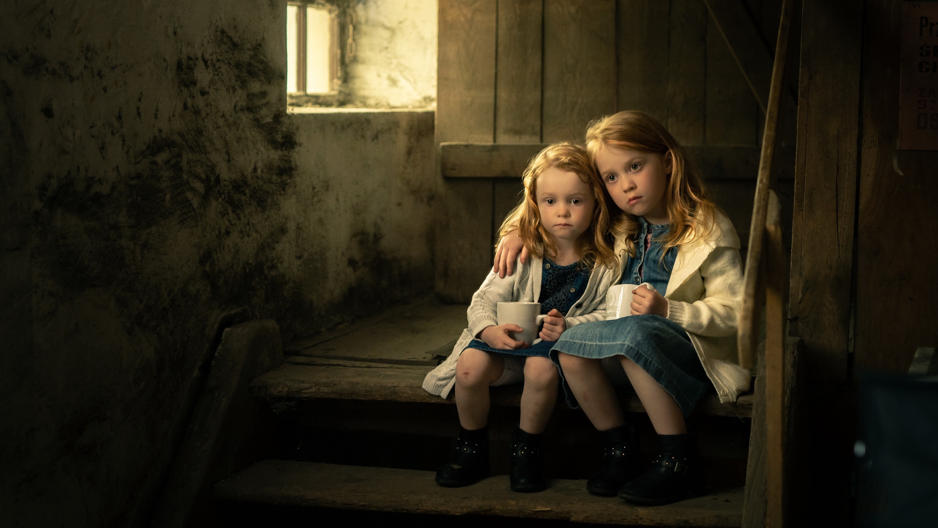 Две маленькие сестры пьют какао на ступеньках дома