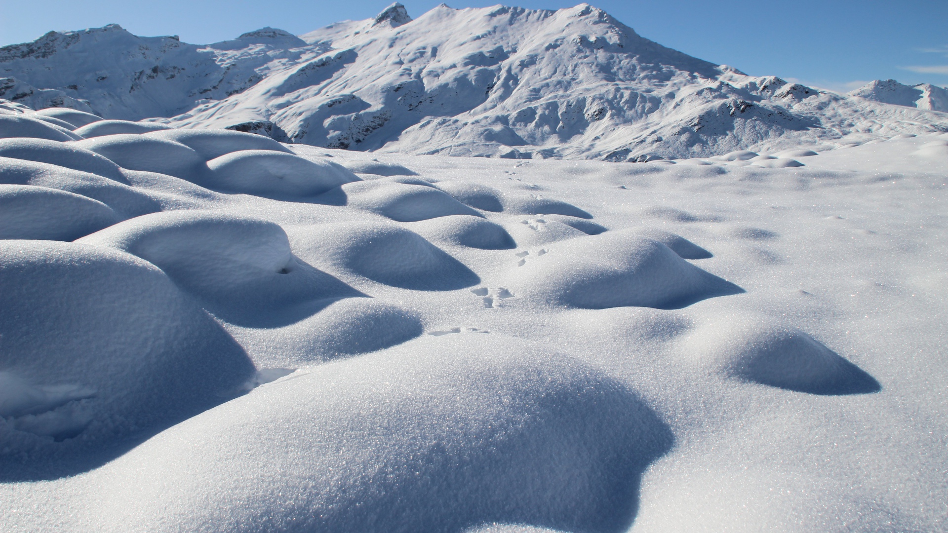Заснеженные камни на поверхности горы в лучах солнца