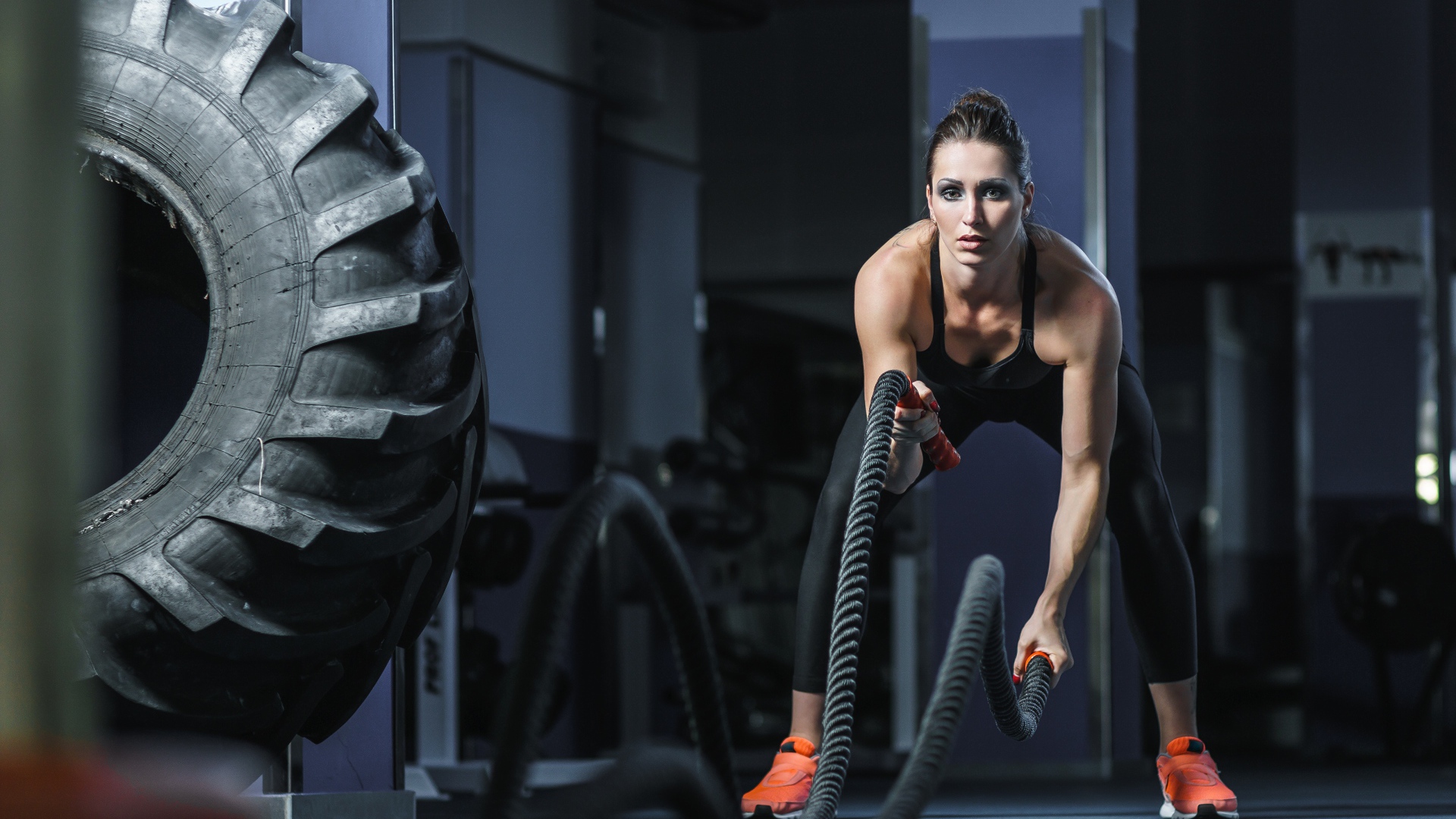 Спортивная девушка занимается с канатами в спортзале 