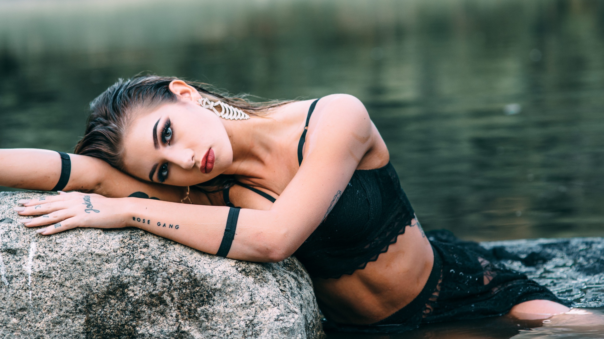 Красивая девушка в черном наряде с татуировками на руках 