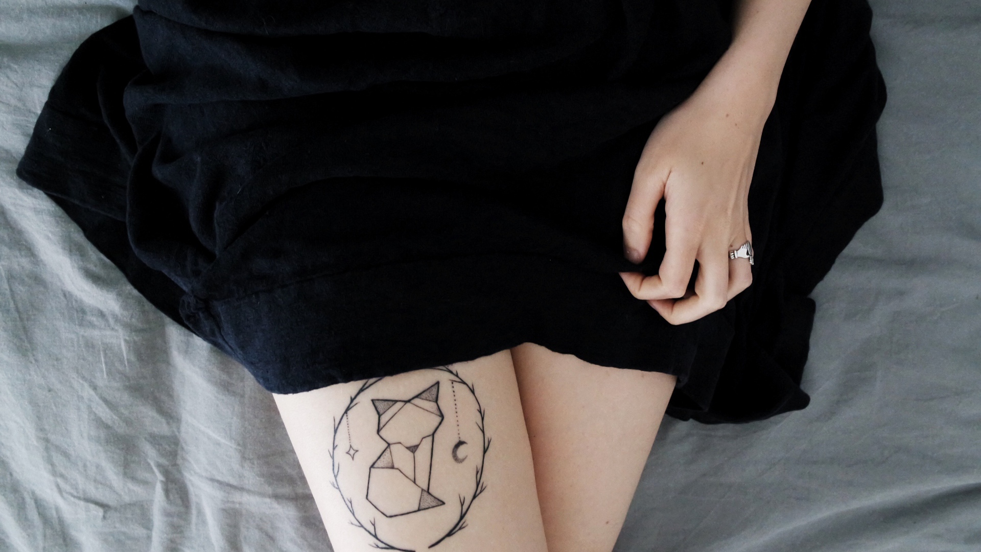 Татуировка лиса на ноге у девушки в черном платье