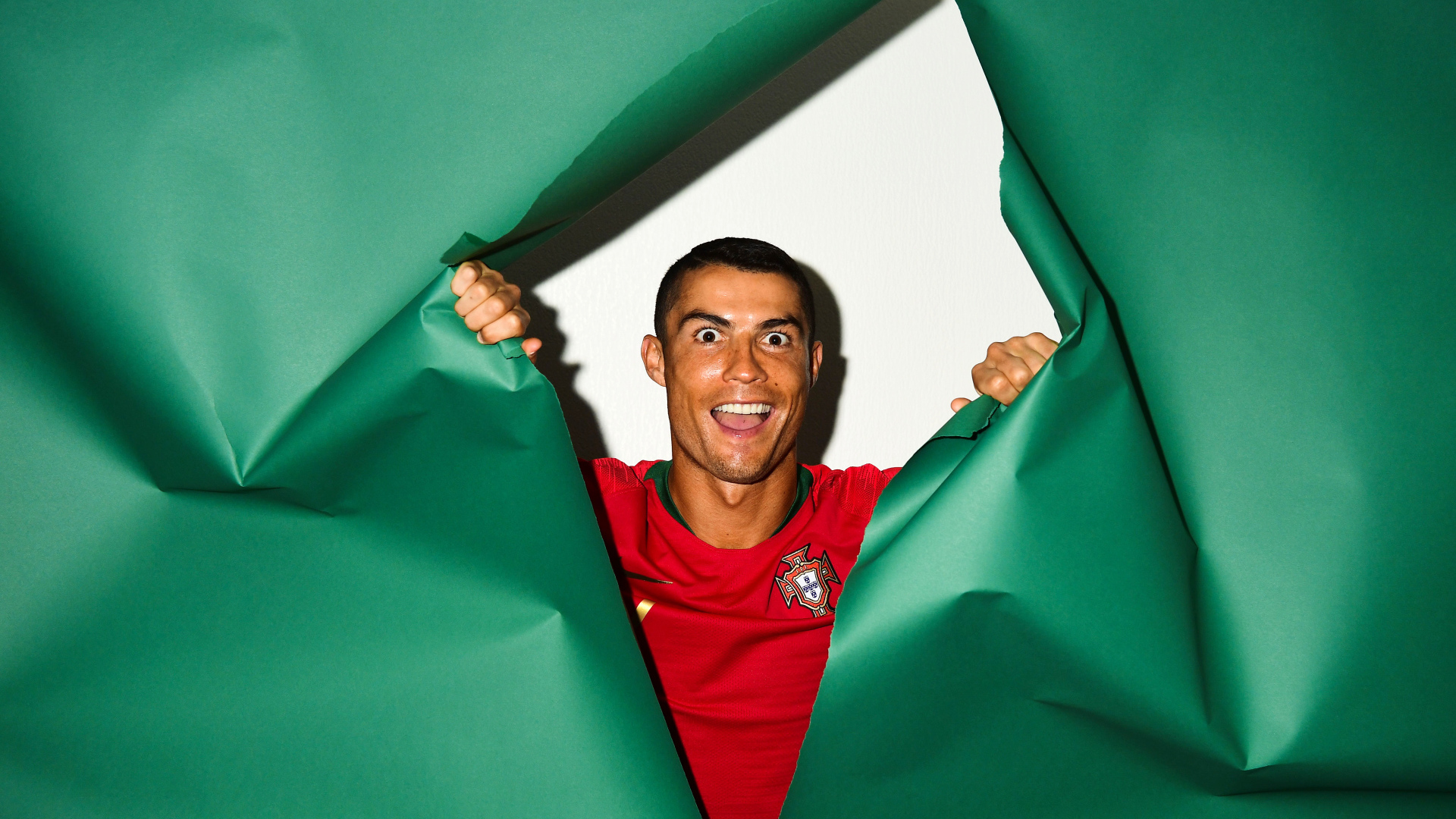 Funny face of football player Cristiano Ronaldo on a green background