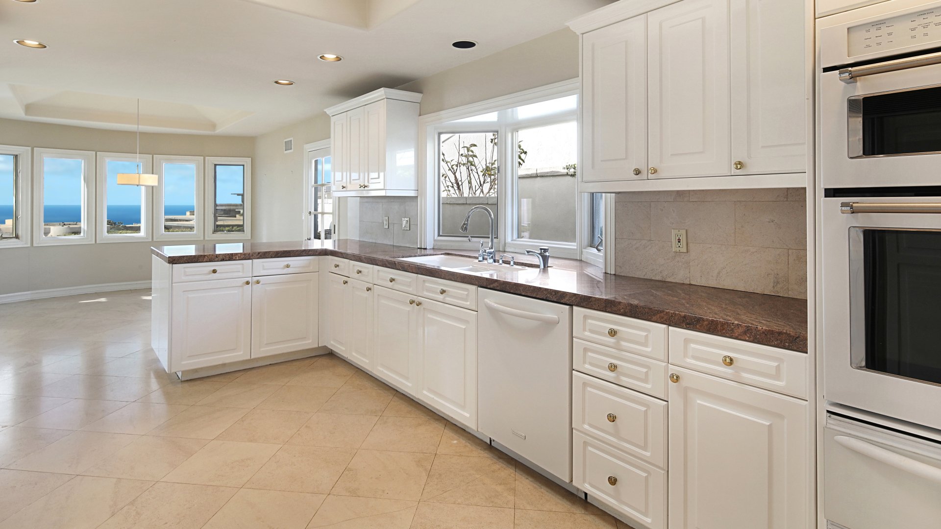 Большая белая кухня с окнами 