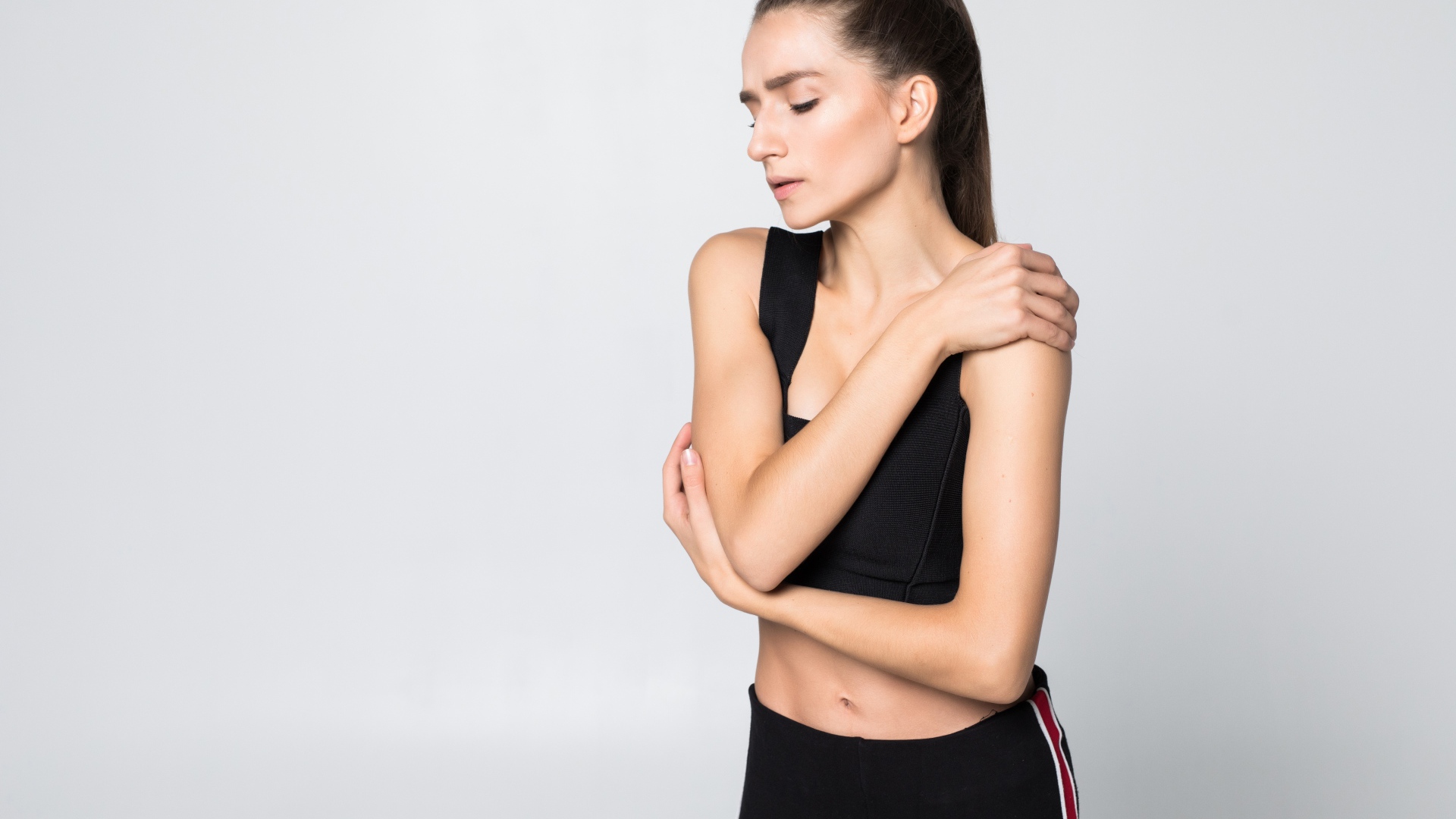 Скромная спортивная девушка на сером фоне