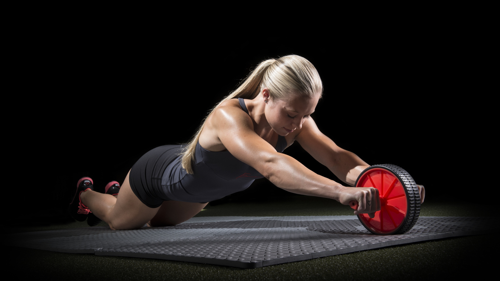 Девушка занимается фитнесом с колесом