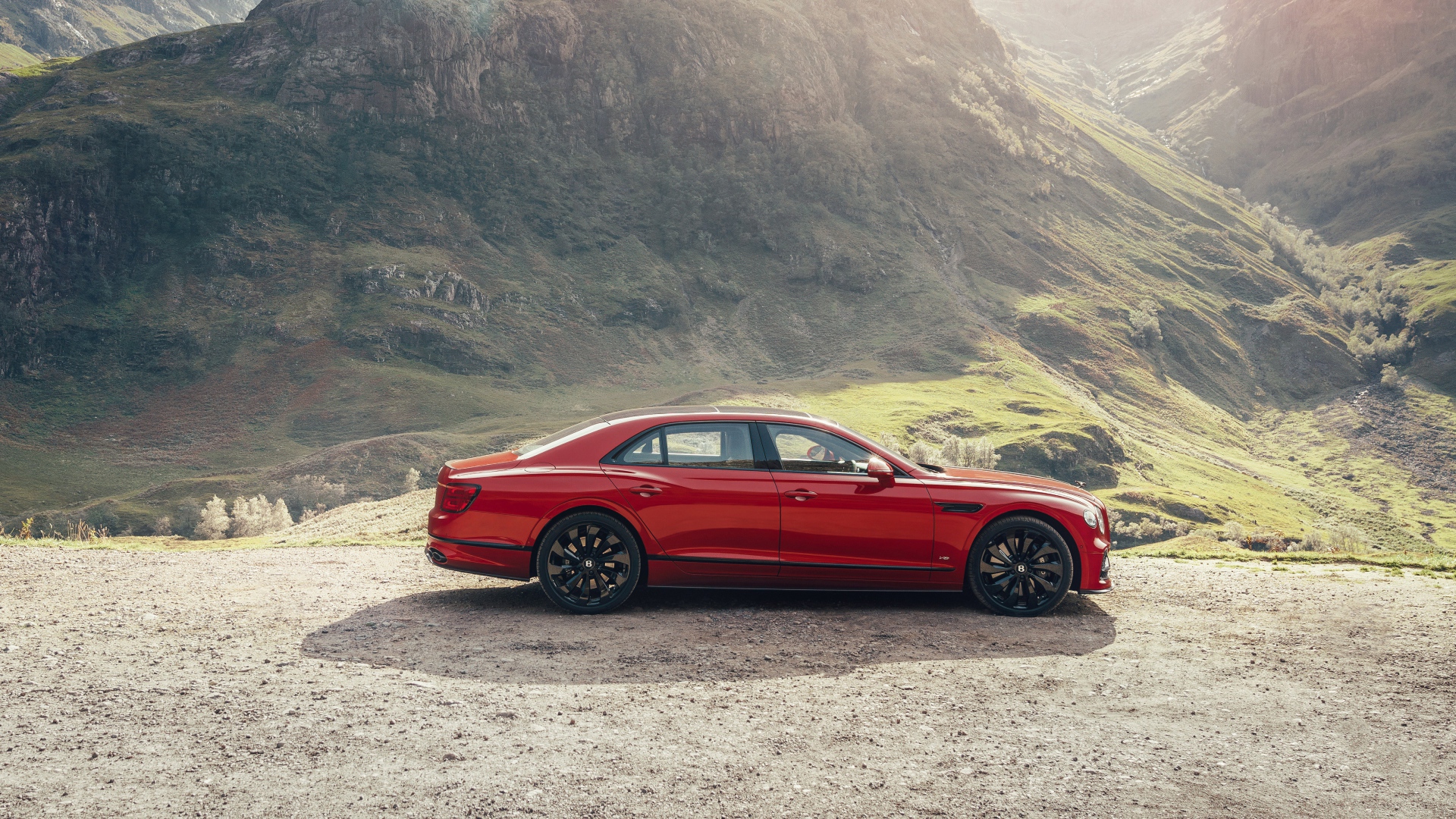 Красный автомобиль Bentley Flying Spur V8 2020 года у горы 