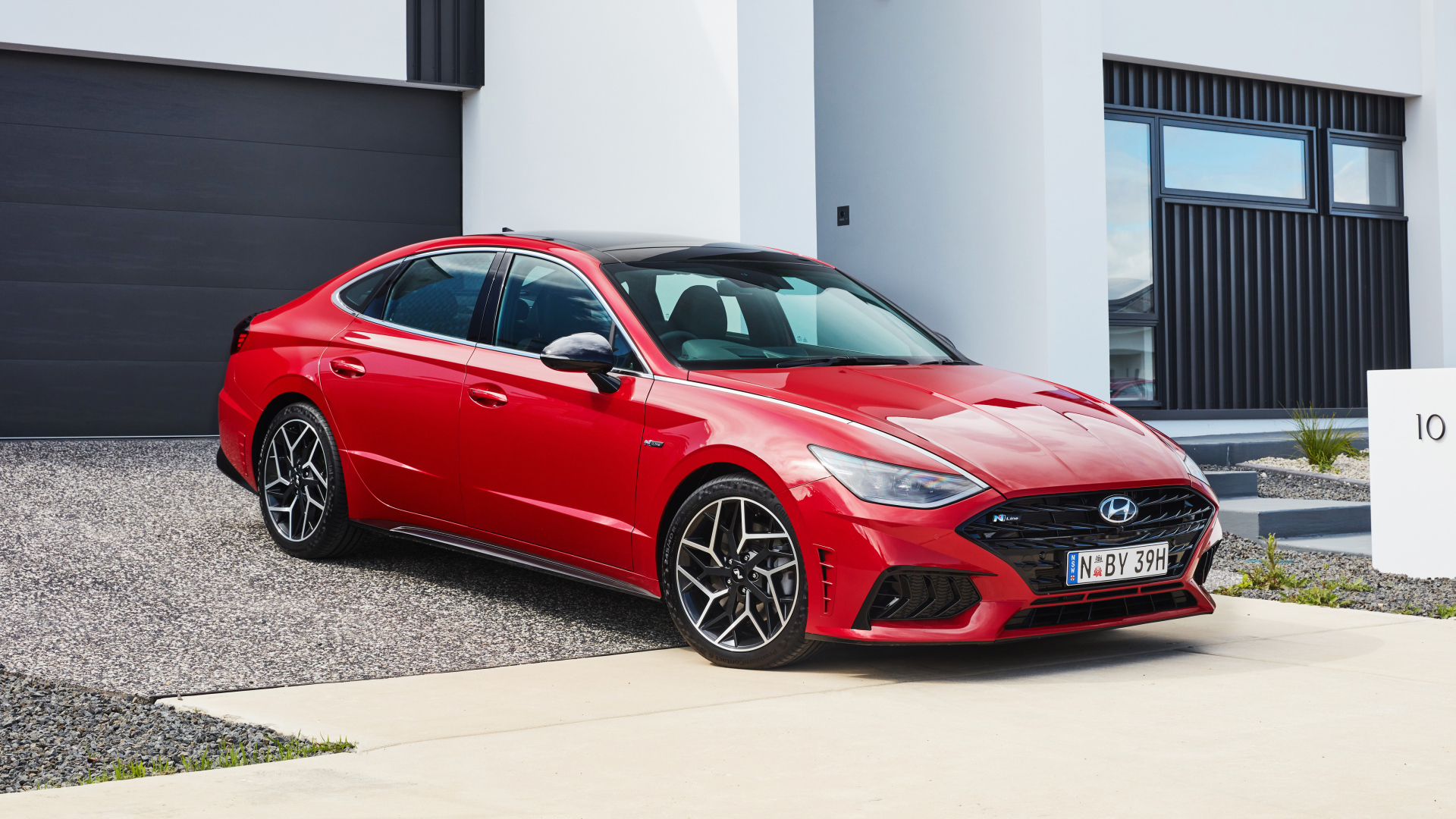 Красный автомобиль Hyundai Sonata N Line 2021 года у гаража