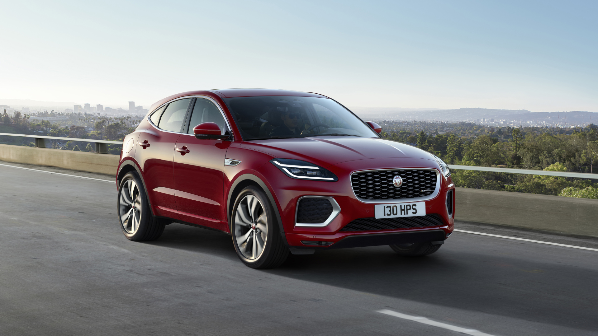 Красный автомобиль Jaguar E-Pace R-Dynamic 2021 года на мосту