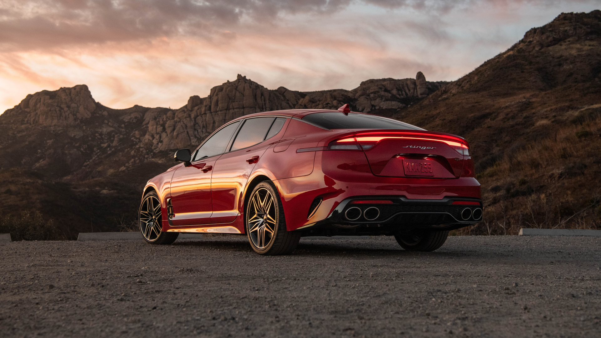 Красный автомобиль Kia Stinger GT, 2022 года в горах вид сзади