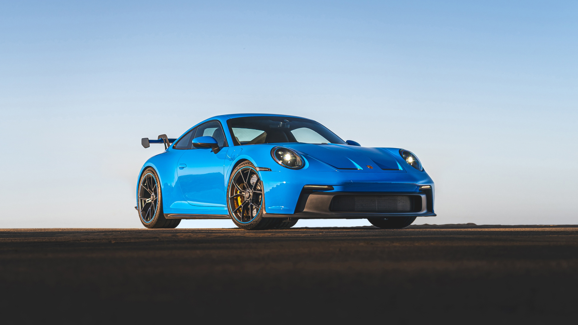 Синий автомобиль Porsche 911 GT3 2021 года на фоне неба