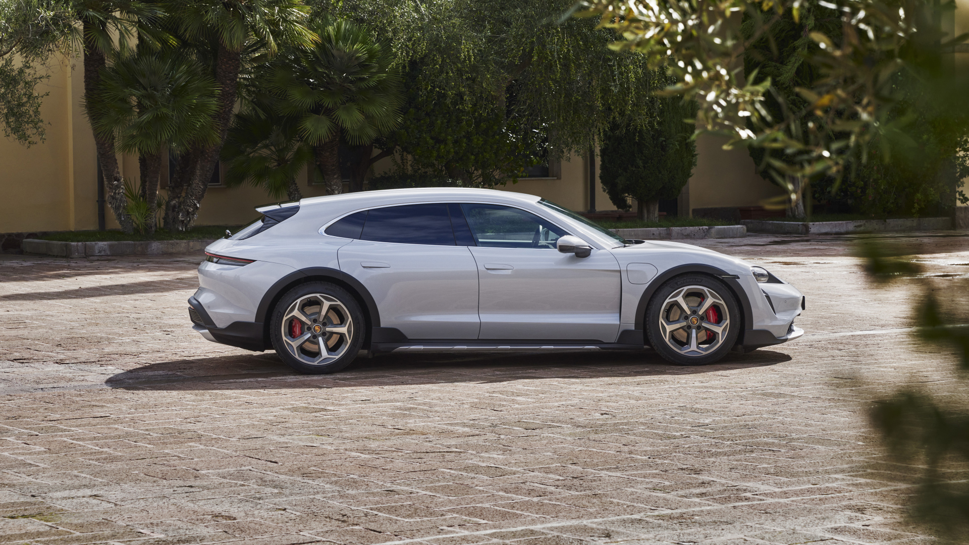 Серебристый автомобиль Porsche Taycan 4S Cross Turismo 2021 года у дома