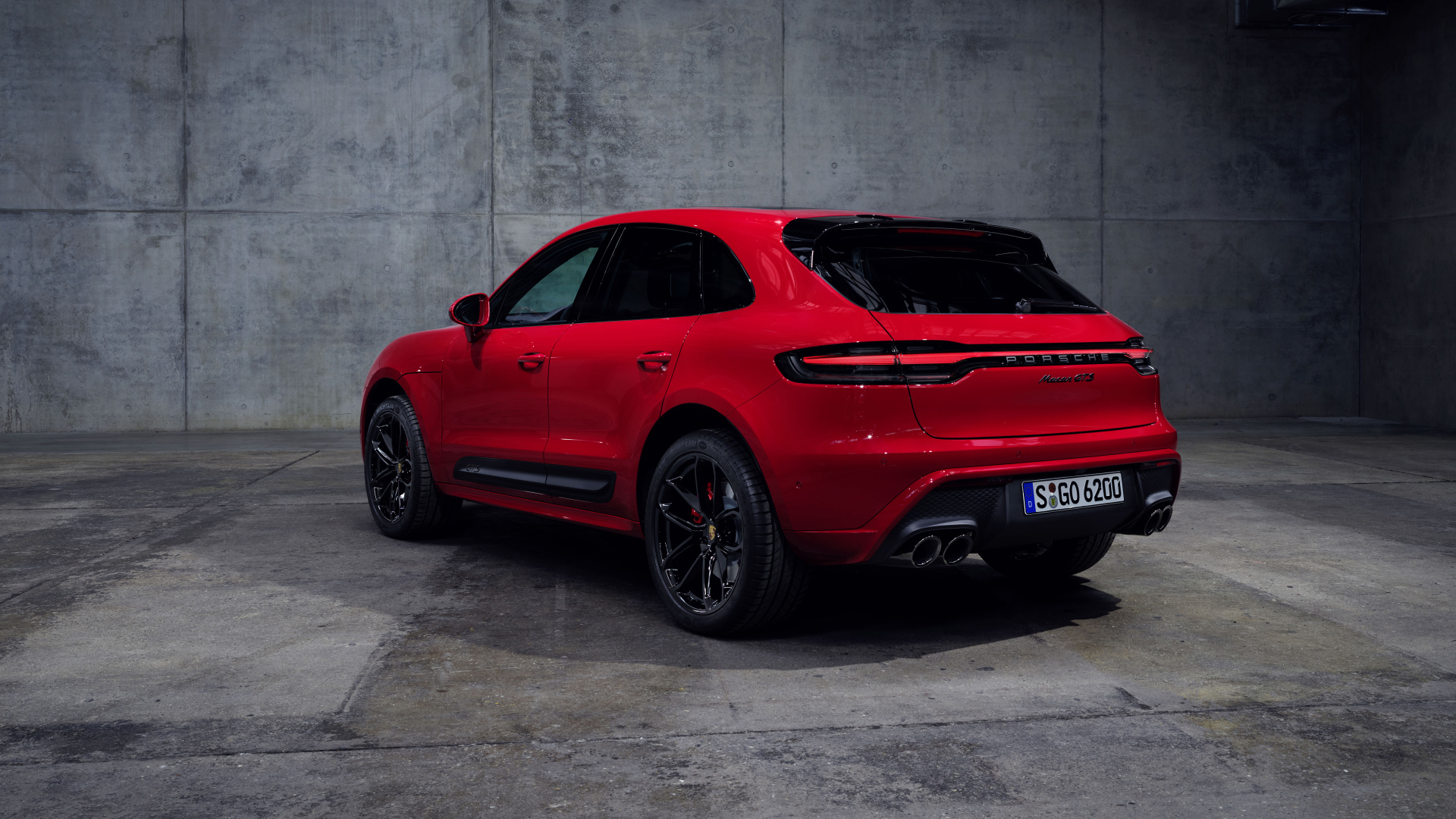 Красный автомобиль Porsche Macan GTS 2021 года на сером фоне вид сзади