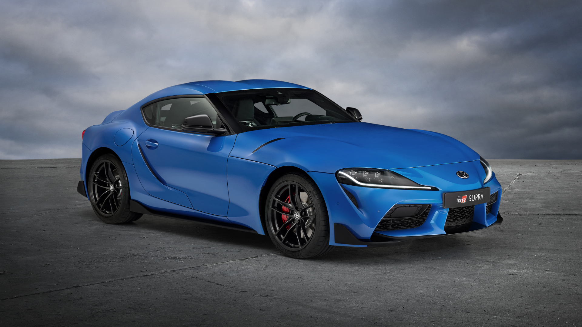 Синий автомобиль Toyota GR Supra, 2021 года на сером фоне