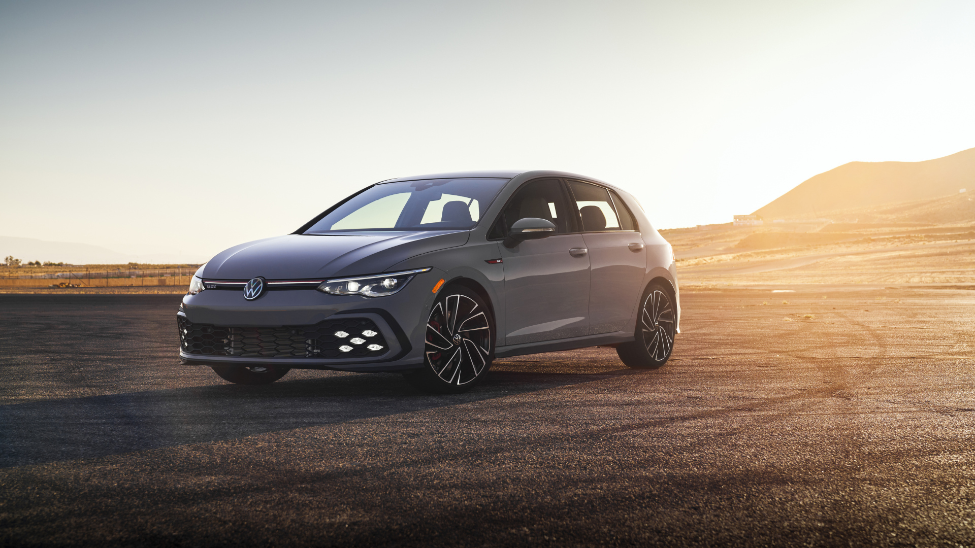 Серебристый автомобиль Volkswagen Golf GTI на фоне заката