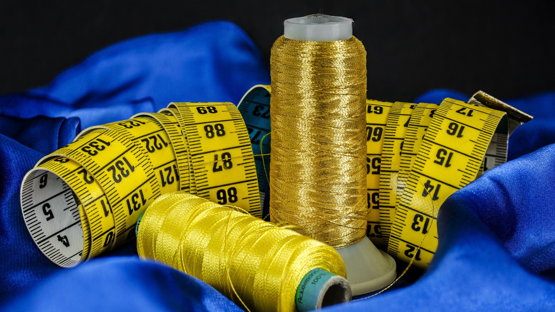 Золотые нитки и сантиметр на голубой ткани 