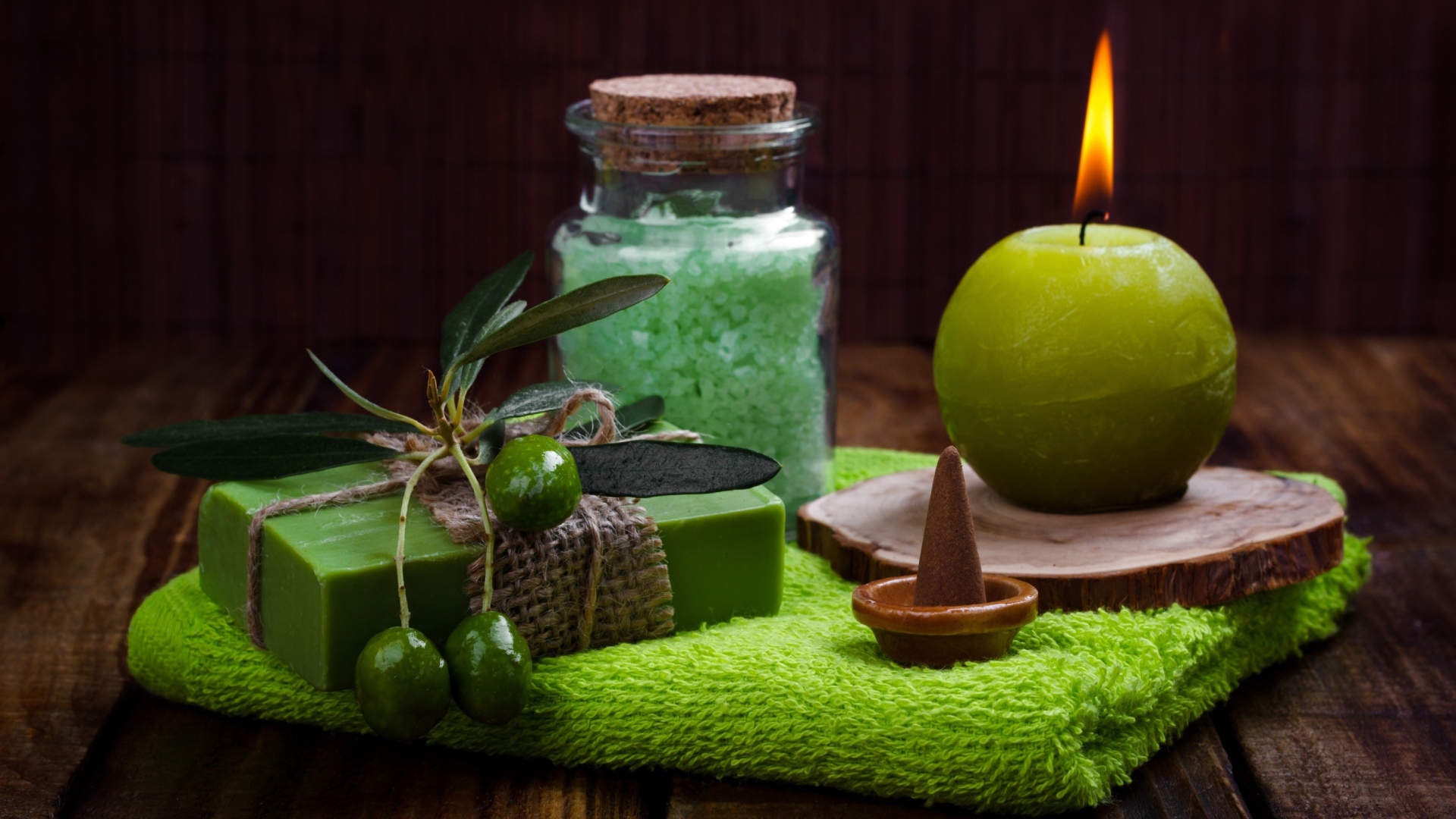 Зажженная свеча и мыло с оливками  и солью 