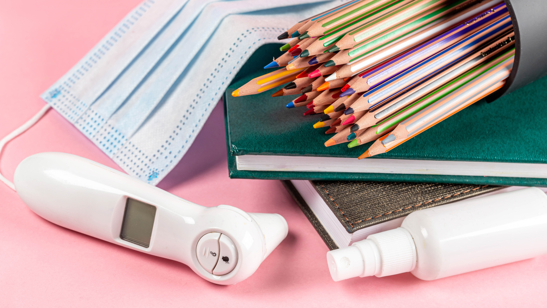 Карандаши, градусник, маска и блокнот на розовом фоне 