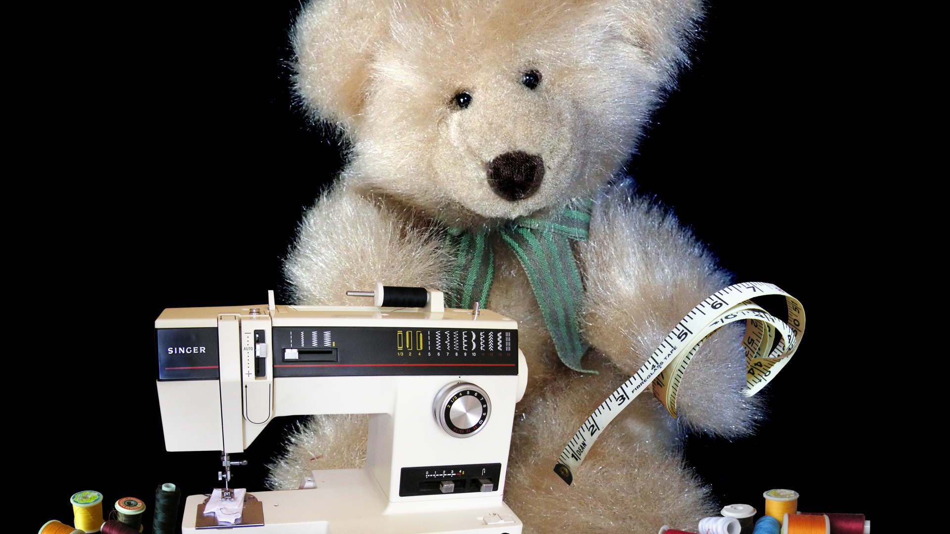 Игрушечный медвежонок со швейной машинкой на черном фоне 