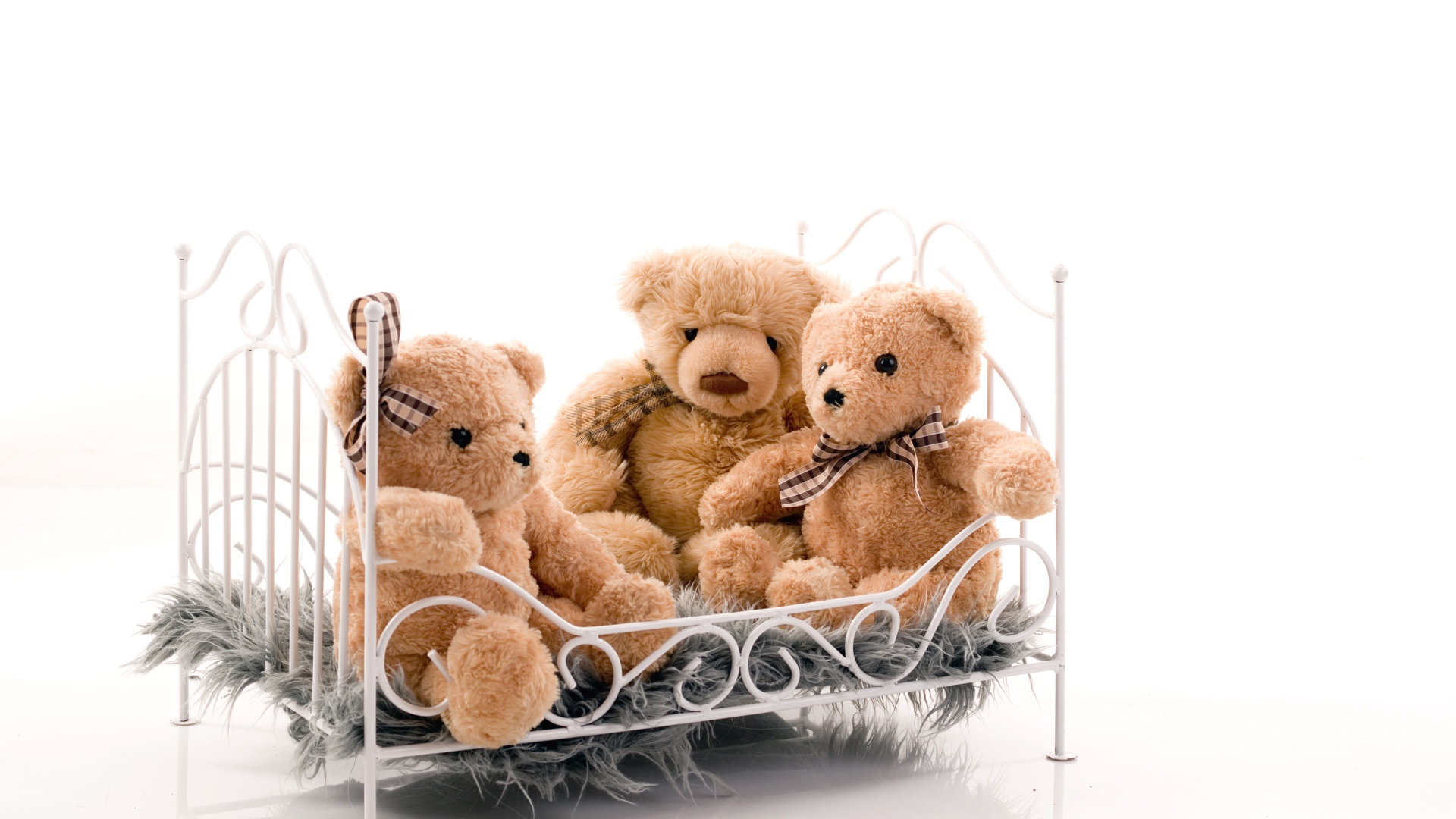 Три игрушечных медведя на кровати на белом фоне