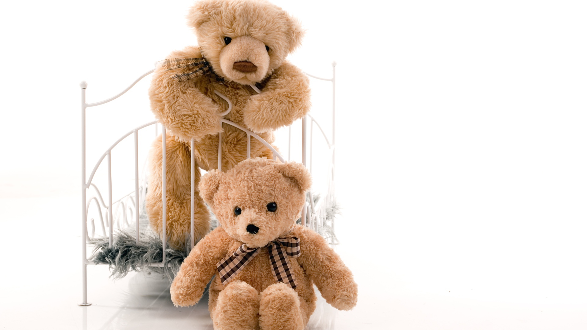 Два игрушечных медведя с кроватью на белом фоне 