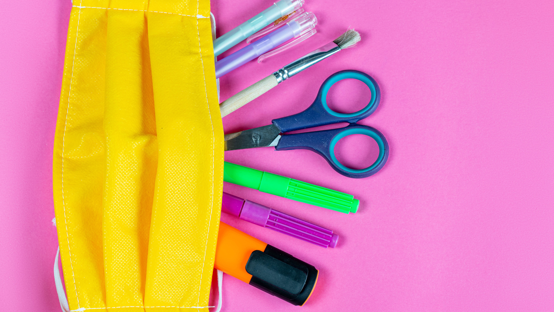 Желтая медицинская маска с ручками и ножницами на  розовом фоне