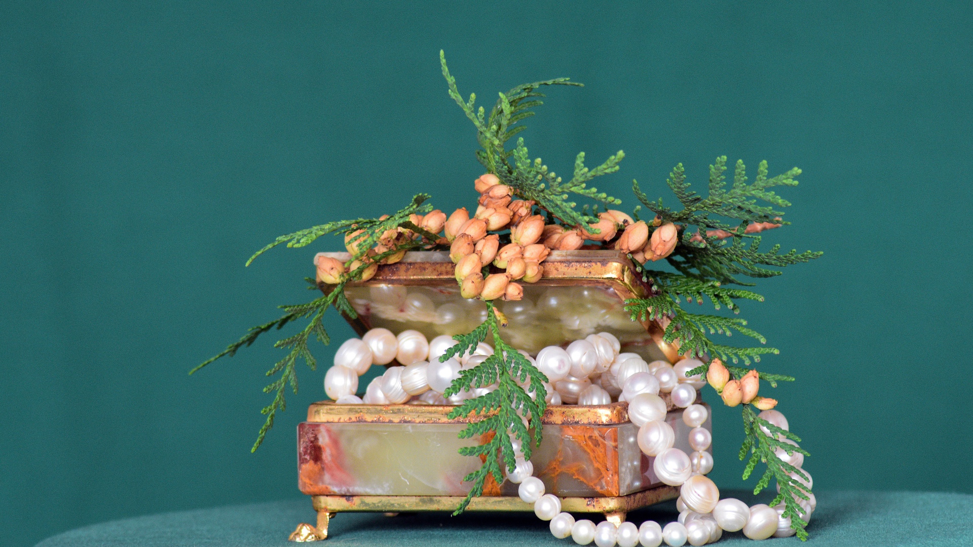 Шкатулка с бусами из жемчуга на зеленом фоне 