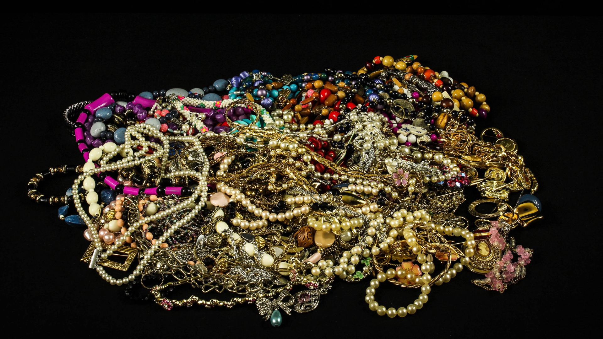 Много драгоценных ювелирных украшений на черном фоне