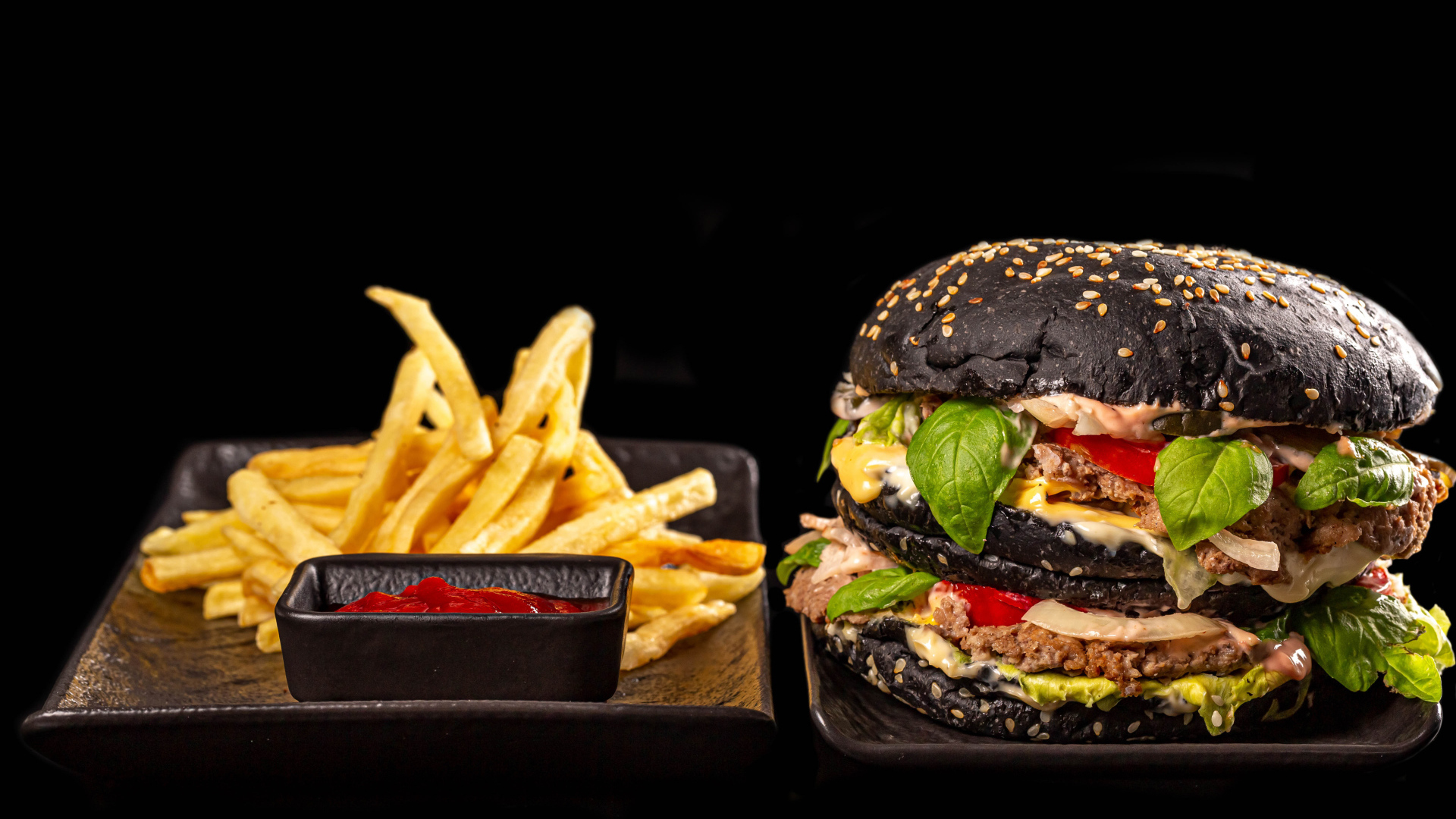 Большой черный гамбургер с картофелем фри и кетчупом 