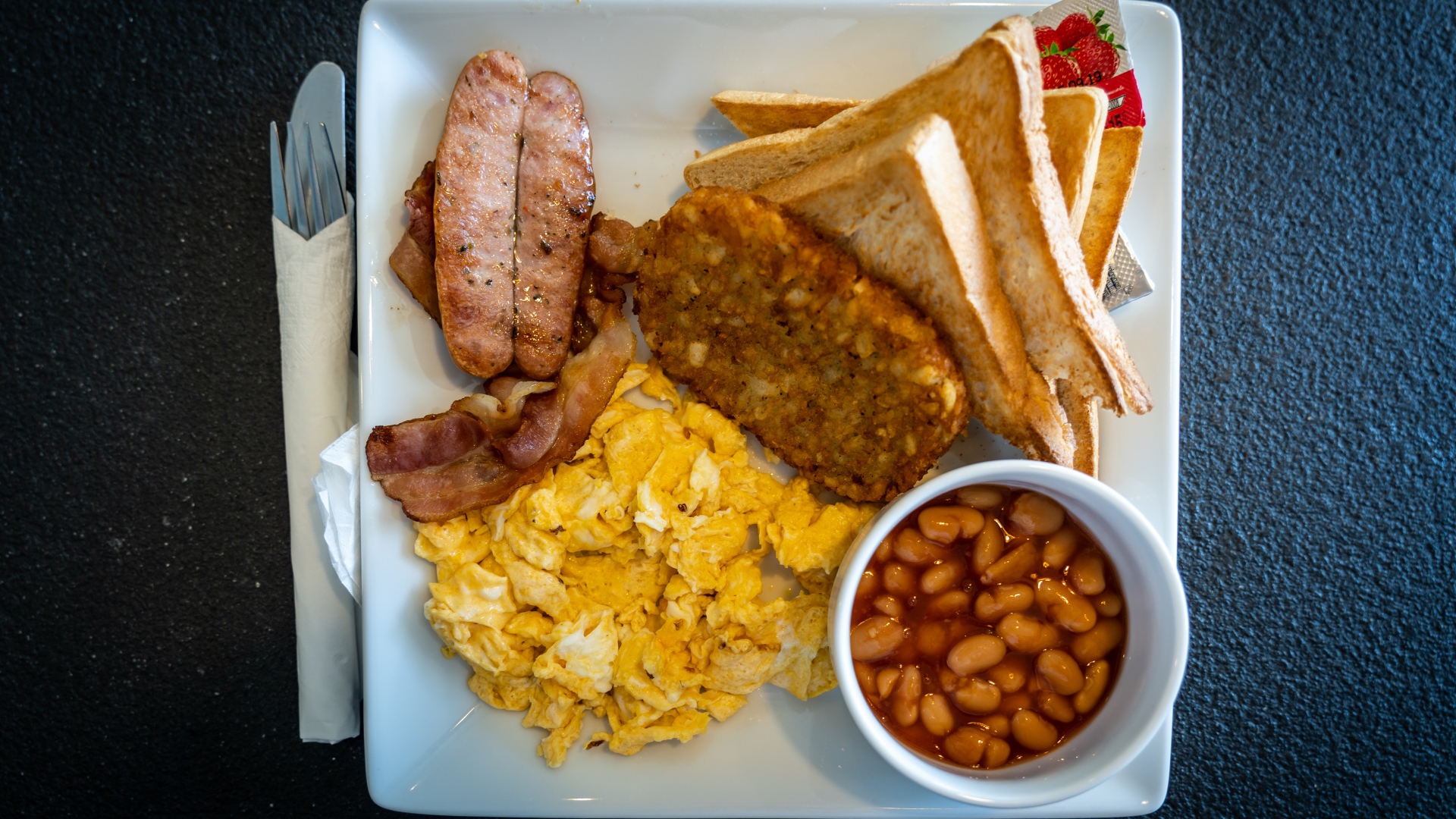 Завтрак на белой тарелке на черном столе 