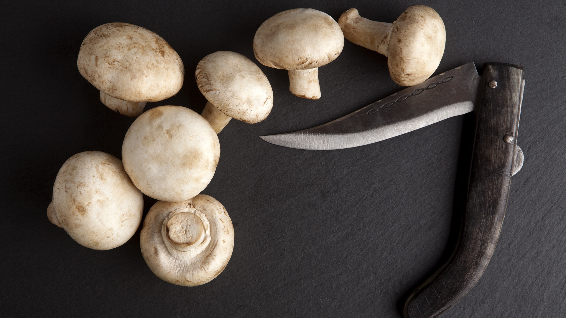 Шампиньоны на сером столе с ножом